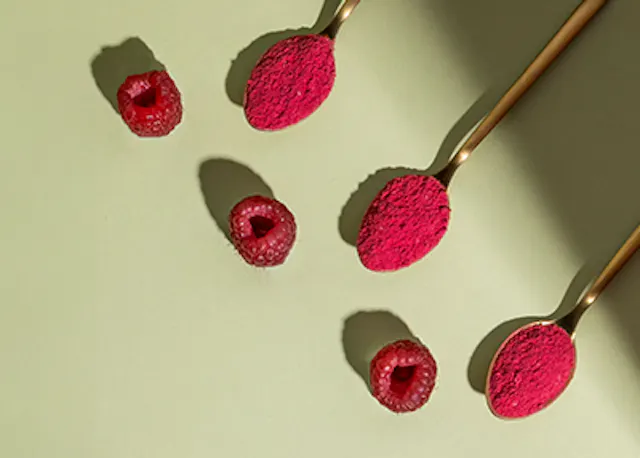 Himbeeren und Löffel mit Himbeerpulver auf einem Tisch .