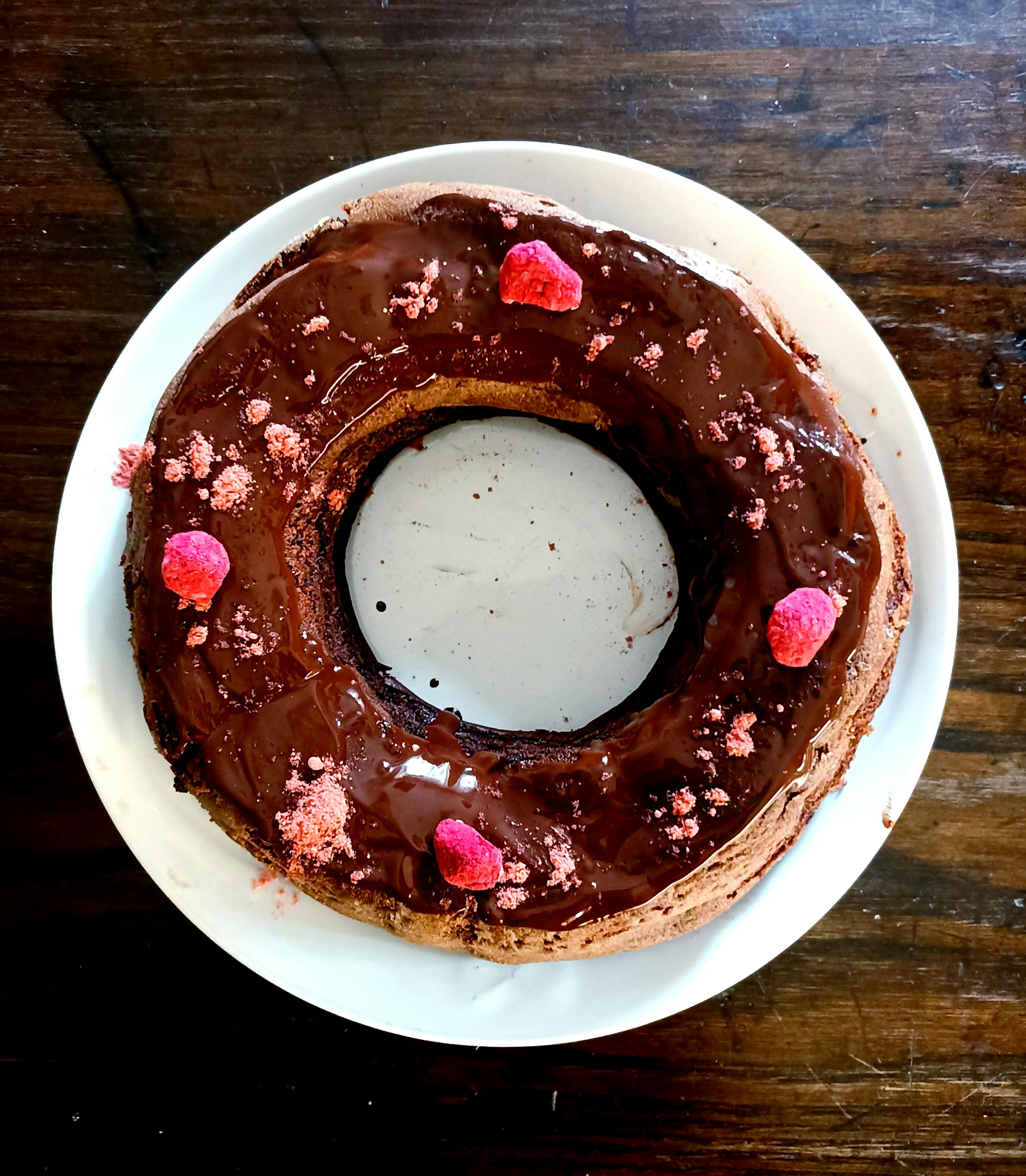 ein Schokoladenkuchen auf einem weißen Teller mit Himbeeren darauf