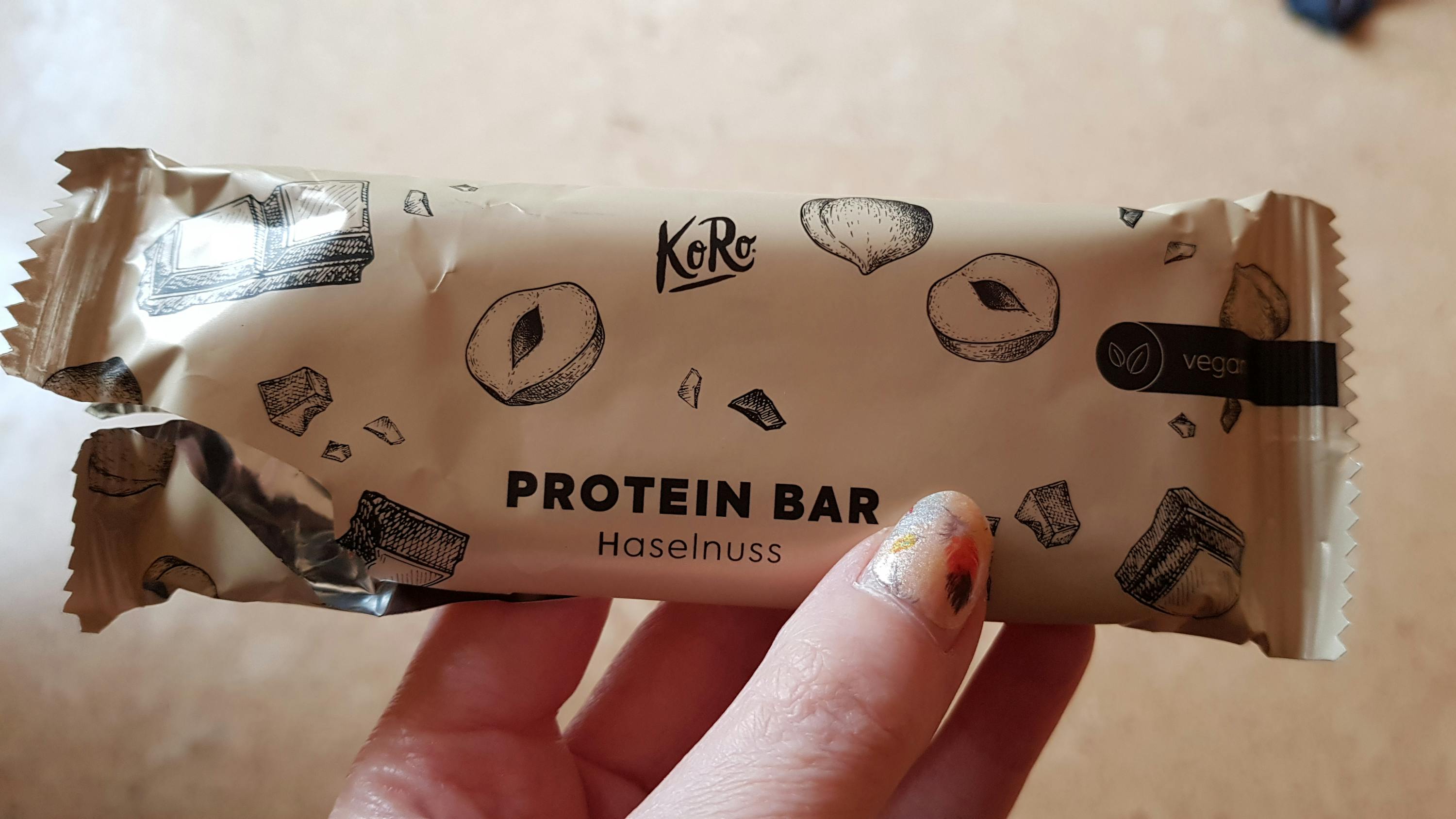 eine person hält einen koko protein bar haselnuss in ihrer hand