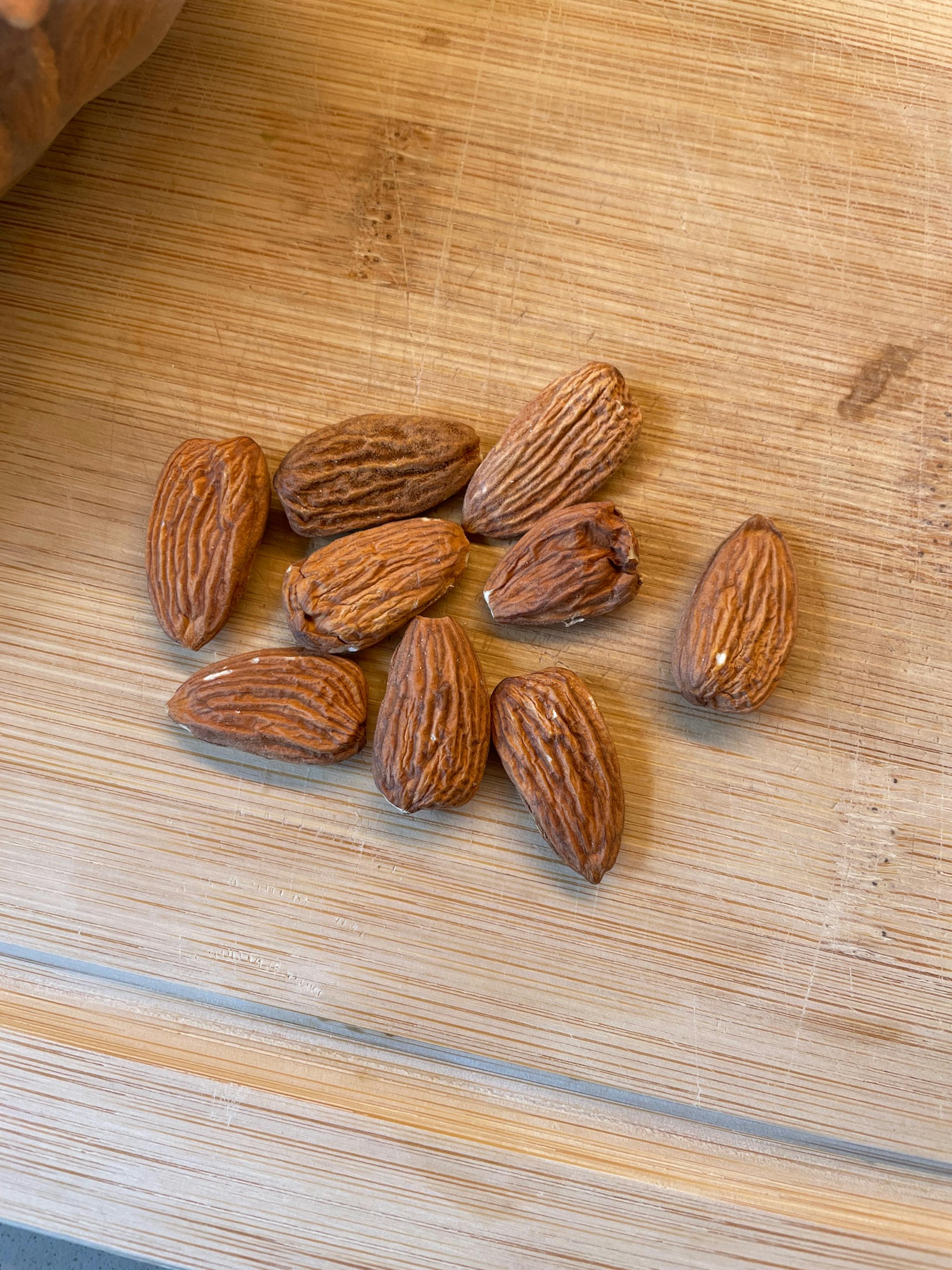 mehrere mandeln liegen auf einem holzschneidebrett.