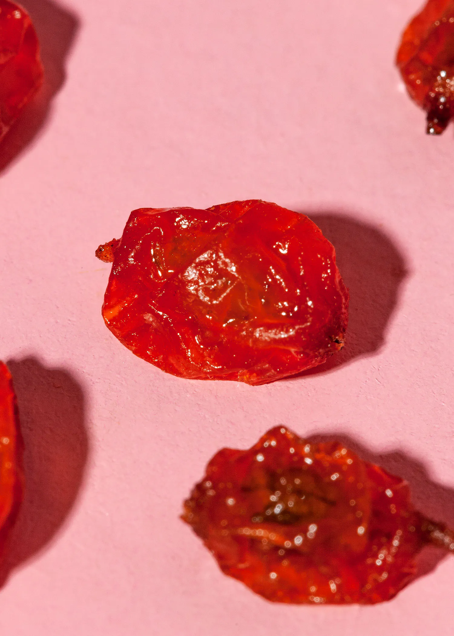 eine Nahaufnahme von getrockneten Tomaten auf rosa Hintergrund