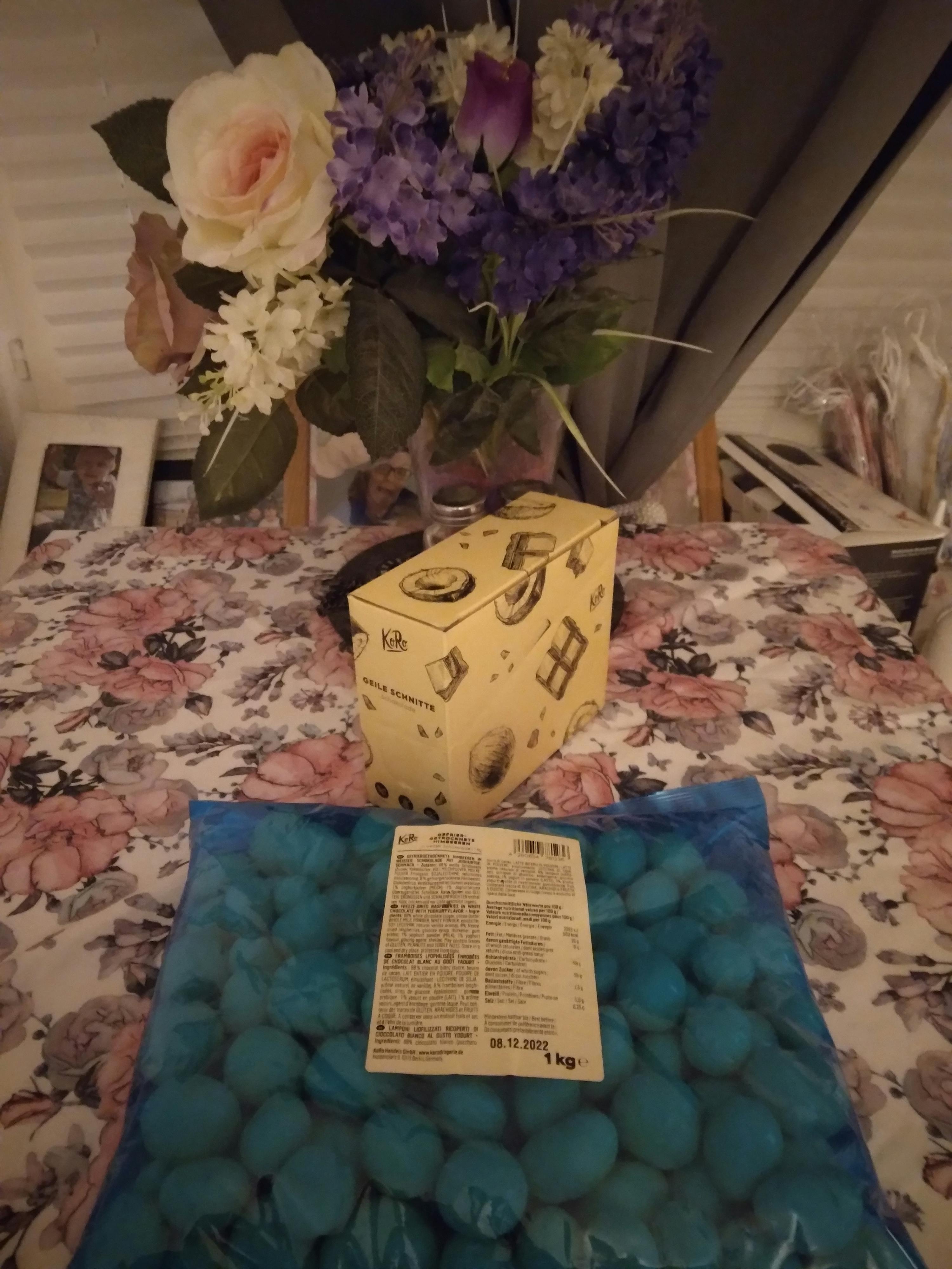 a bag of blue balls sits on a table with flowers