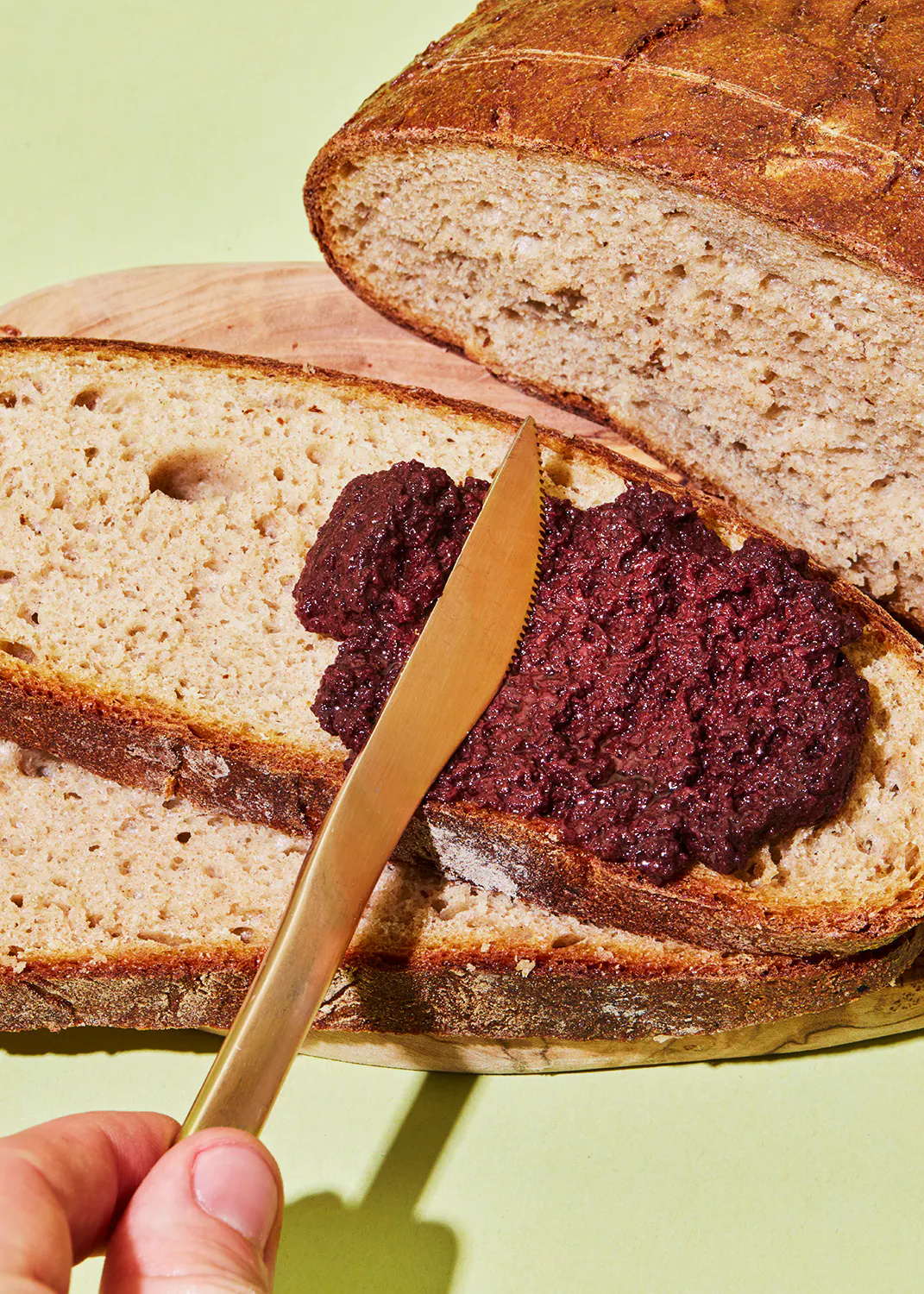 une personne tient un couteau devant un morceau de pain