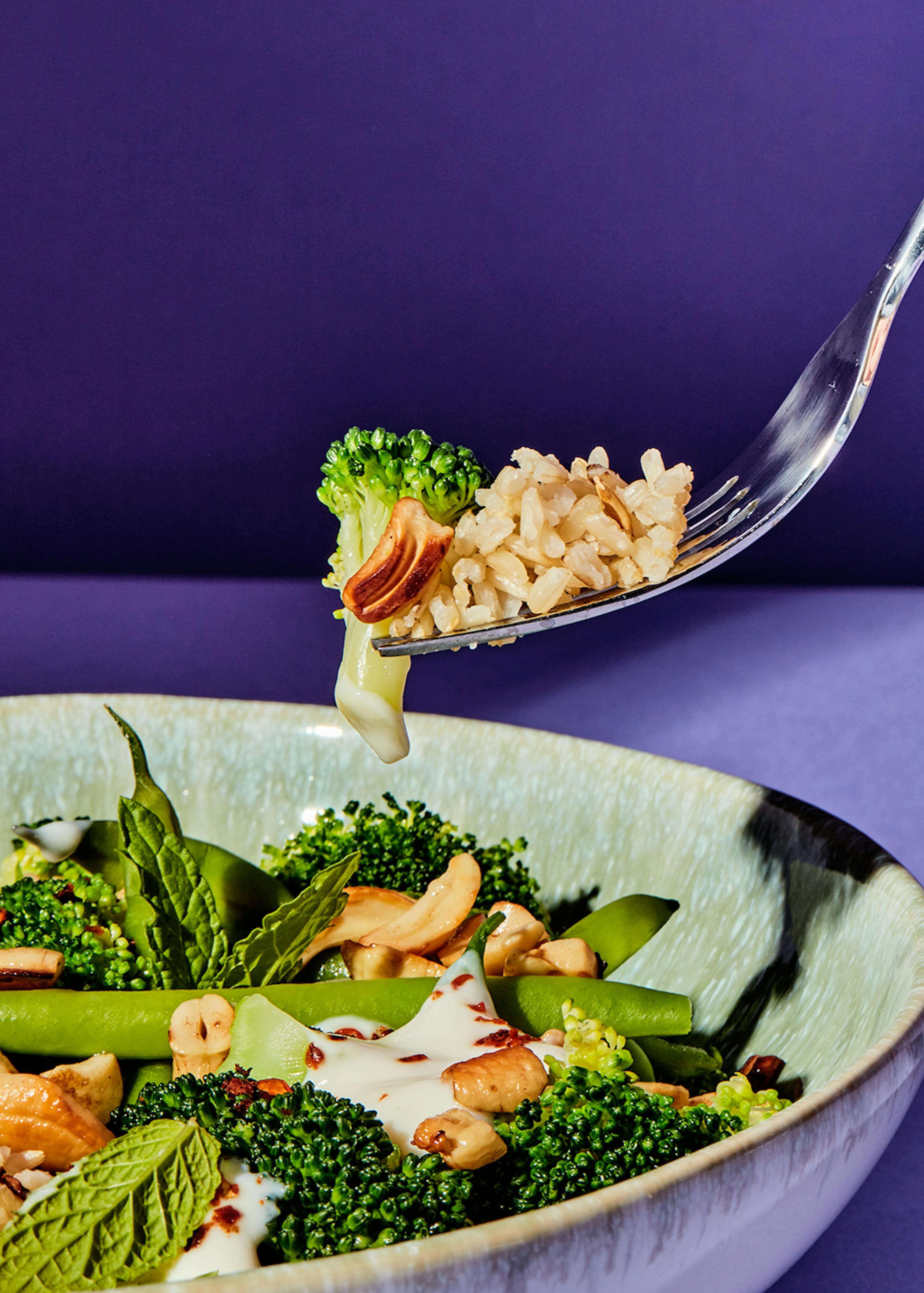 a plate of food with broccoli and rice on a fork