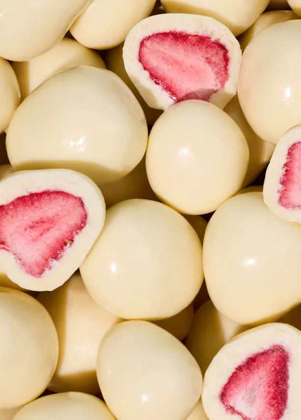a pile of white chocolate covered strawberries with a red center