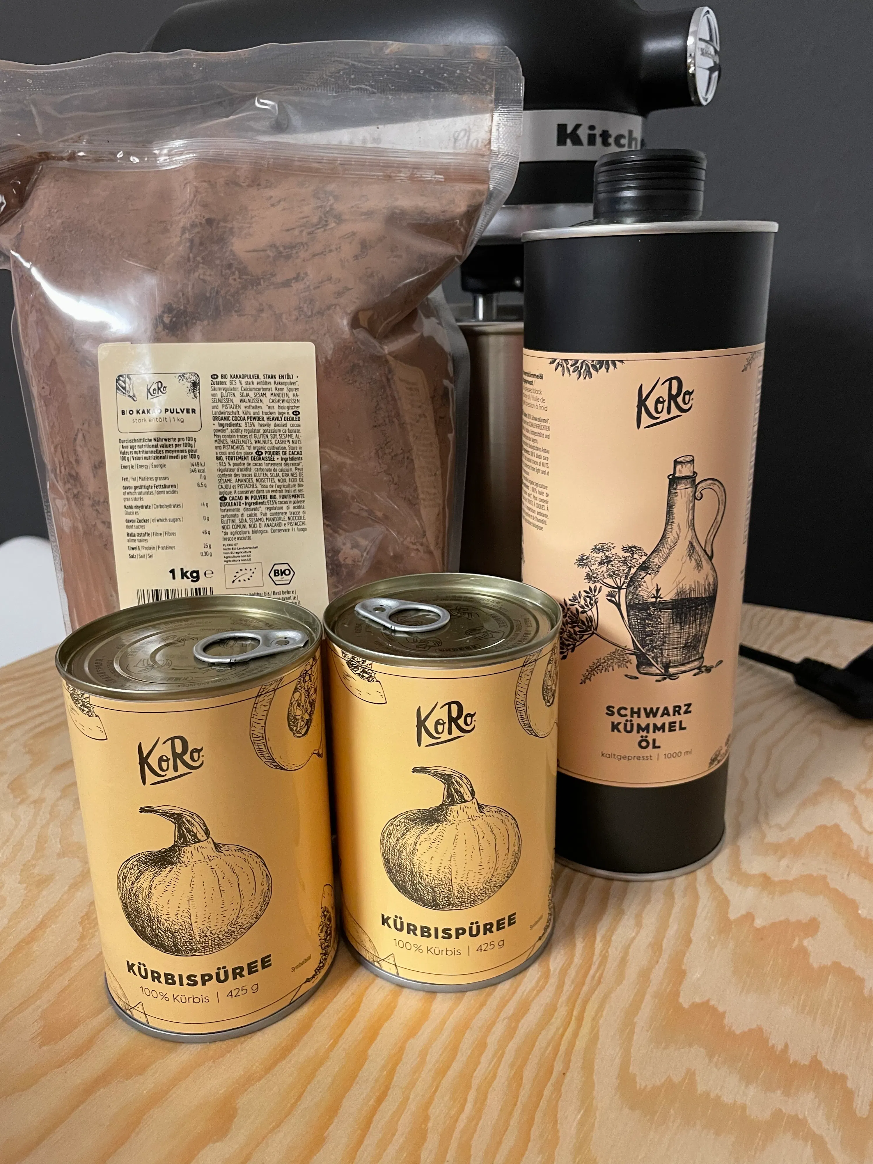 drei Dosen Kürbispüree neben einer Dose schwarzem Knoblauchöl