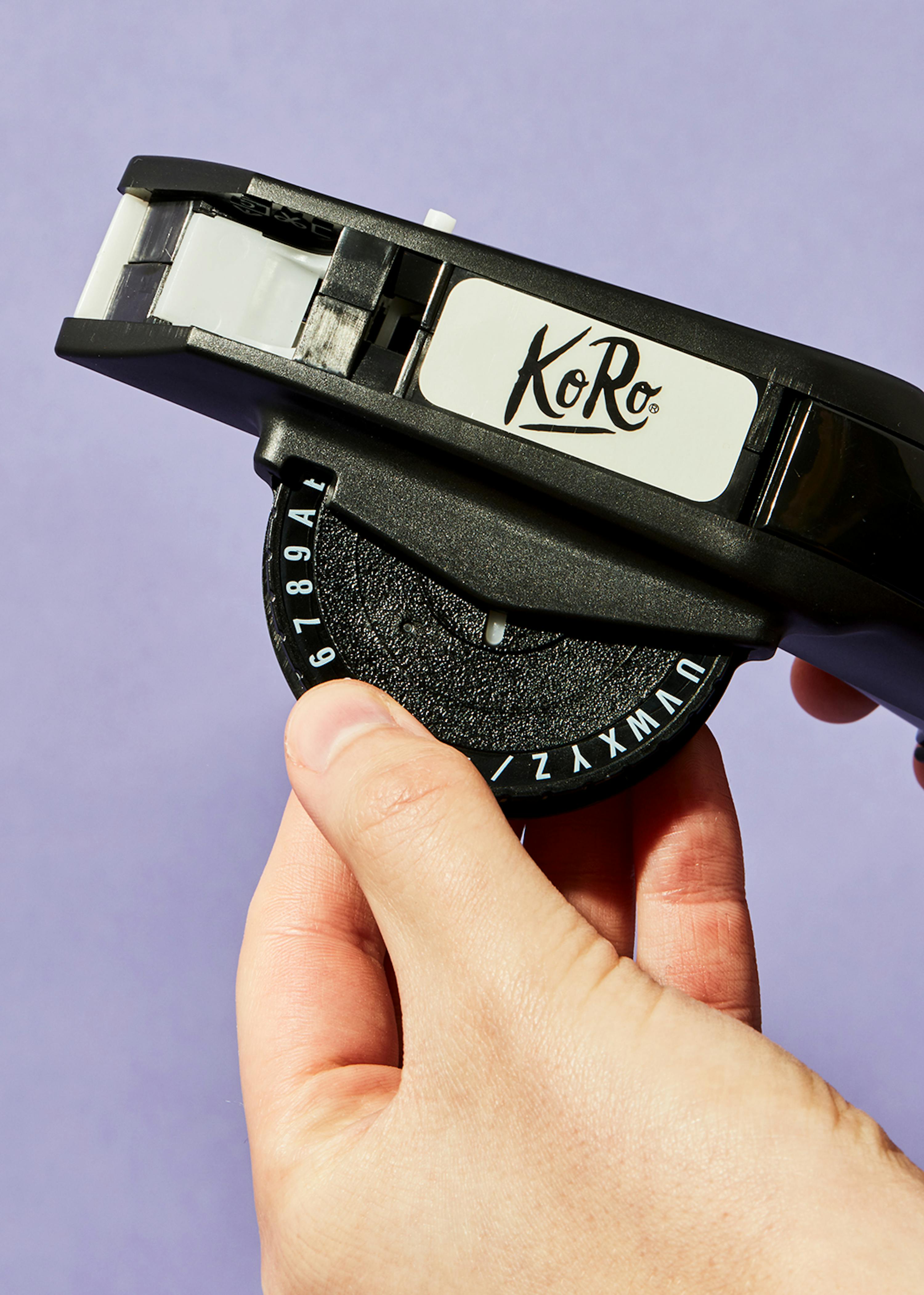 a person is holding a koro tape dispenser in their hand