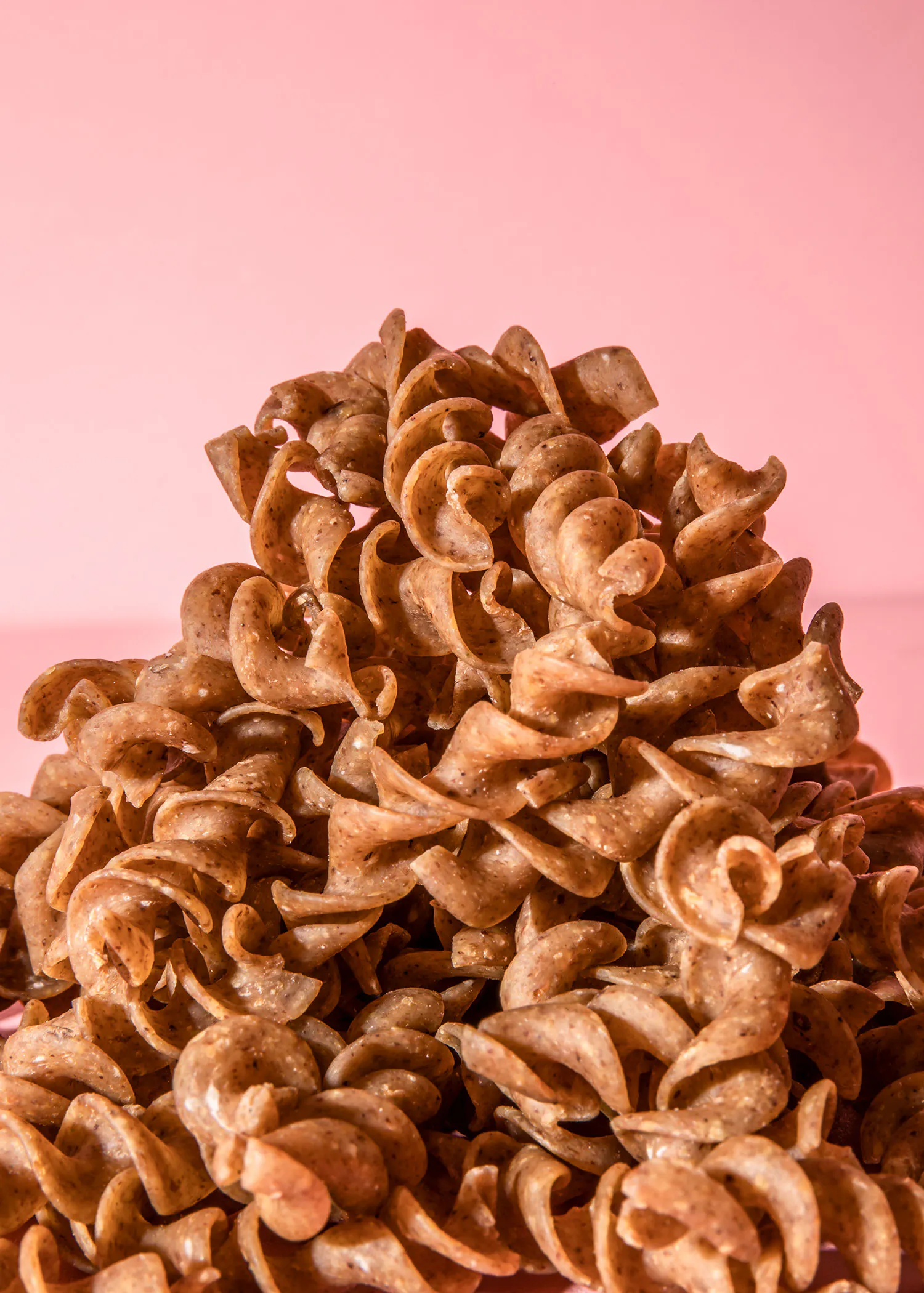 un tas de pâtes torsadées sur fond rose