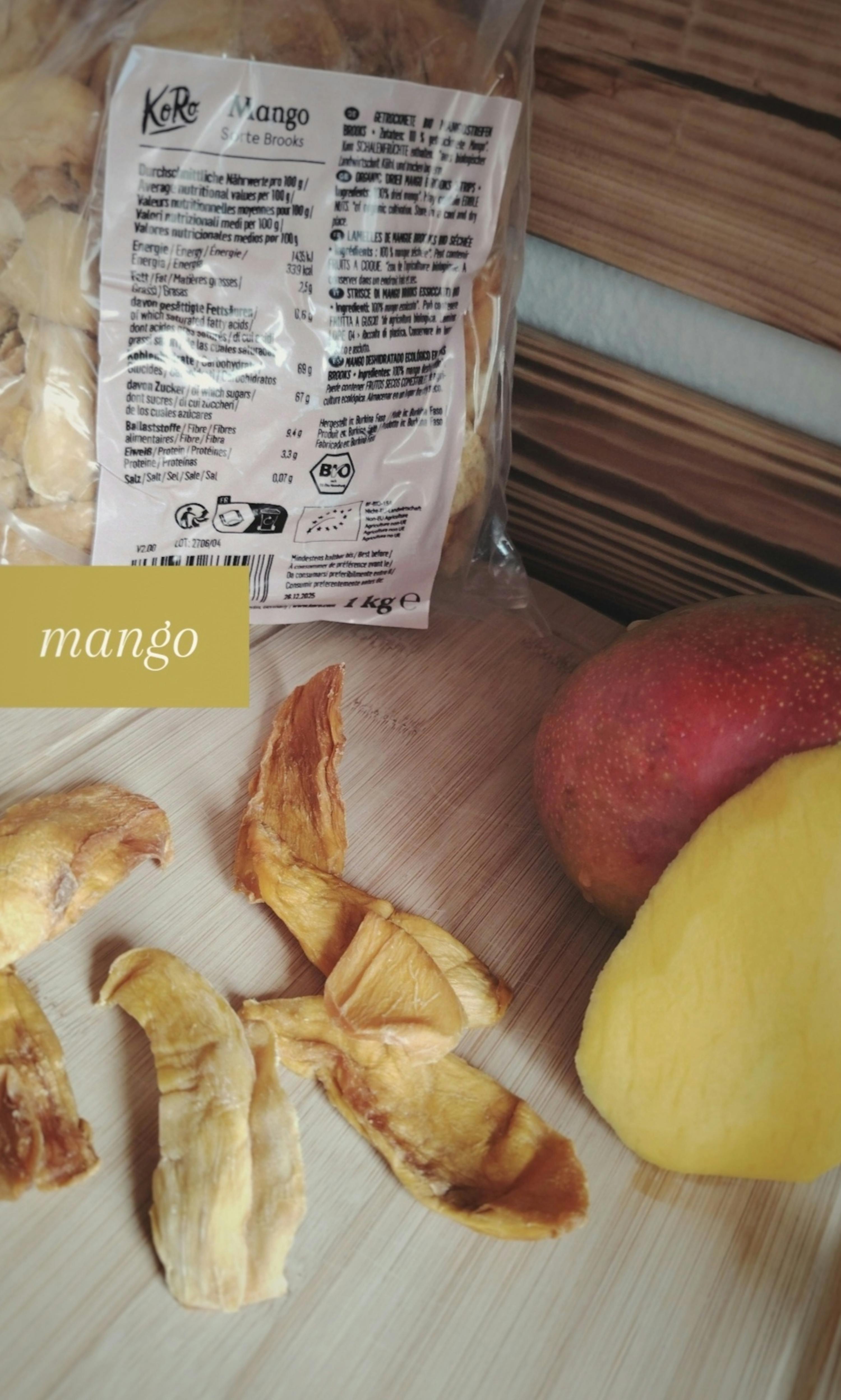 ein Stück getrockneter Mango liegt auf einem Schneidebrett neben einem Plastikbeutel