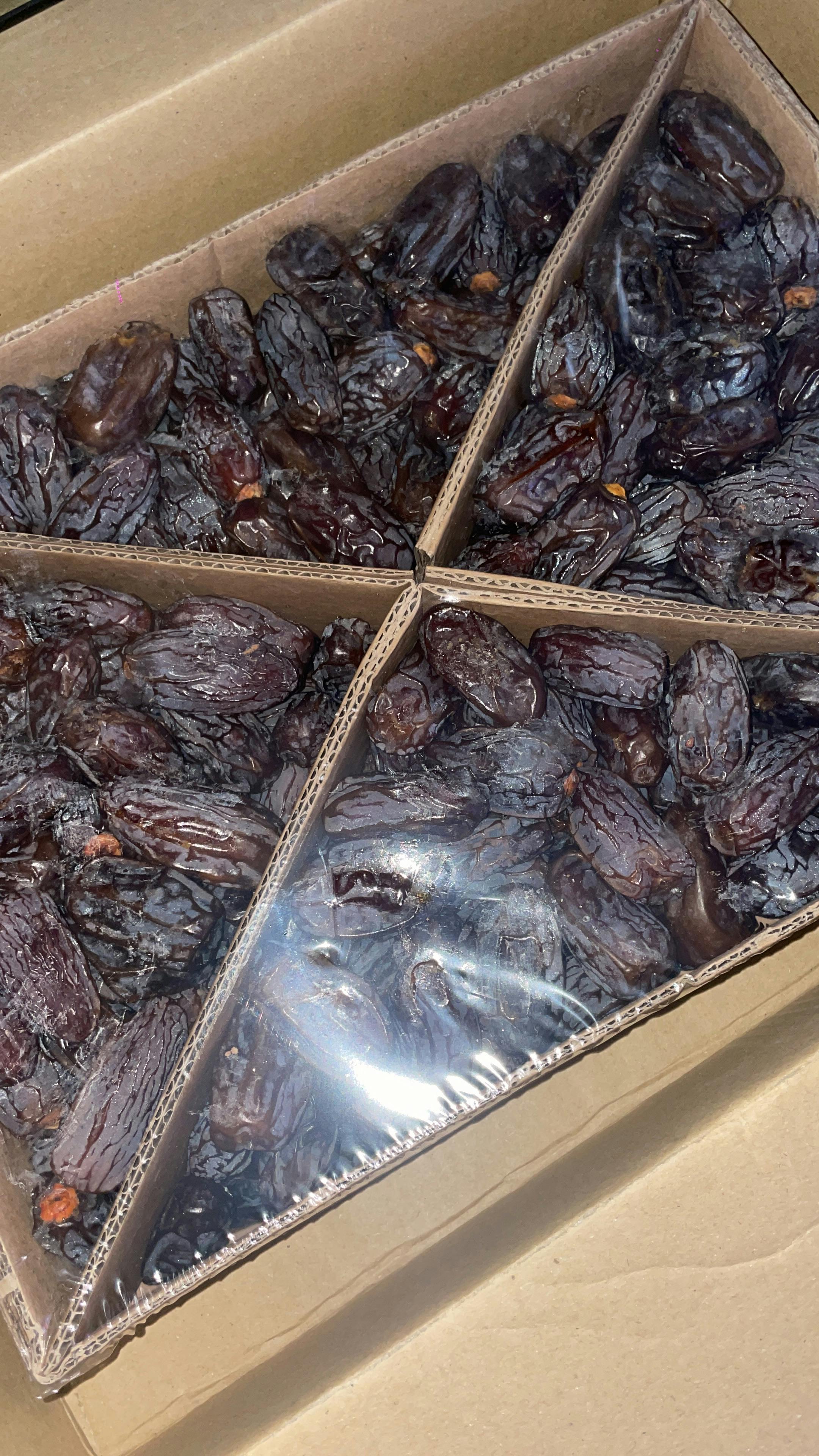 eine Schachtel mit schwarzen Datteln in einer Plastikhülle