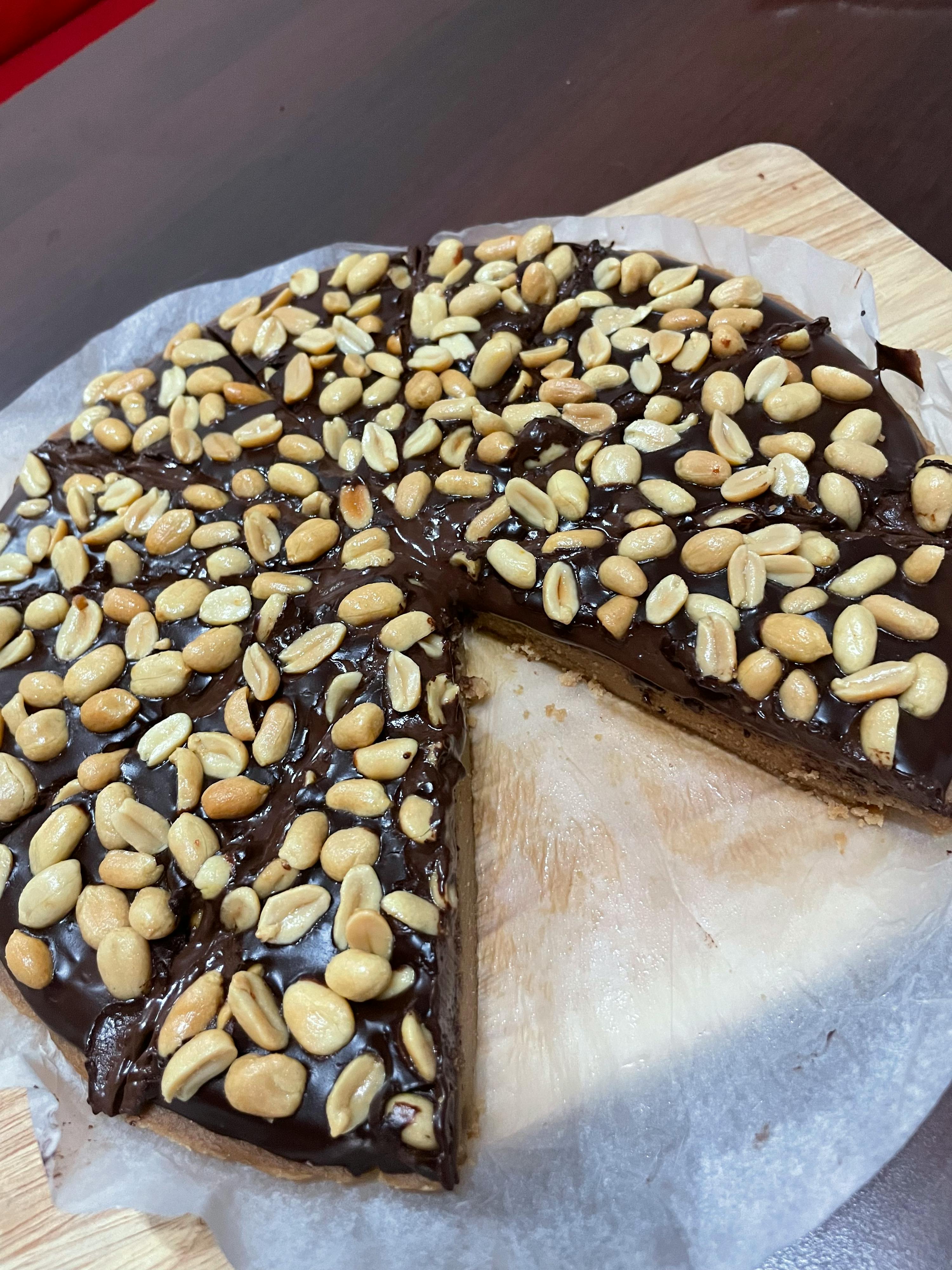 a chocolate cake with peanuts and a slice taken out of it