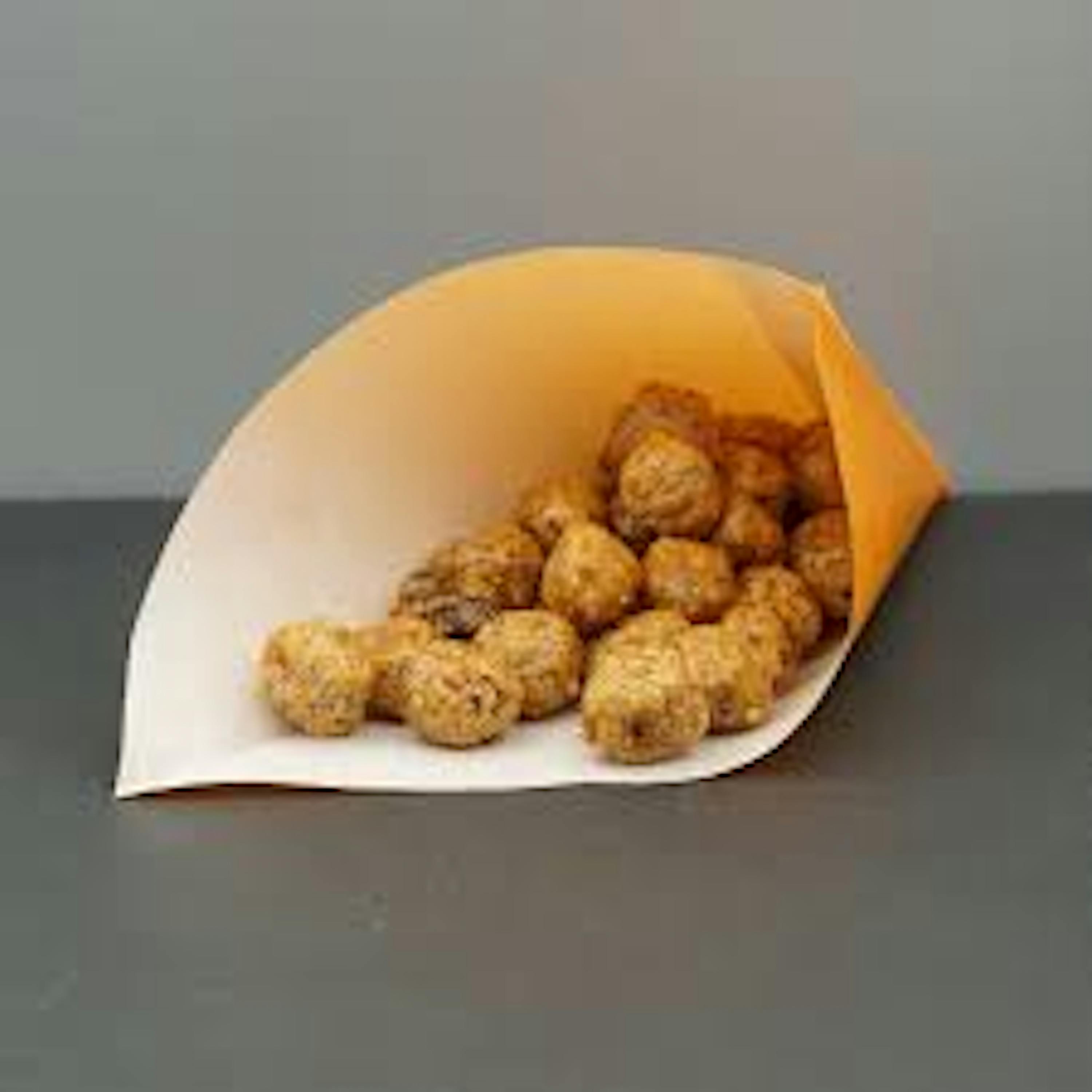 un sacchetto di carta pieno di pollo fritto è seduto su un tavolo .