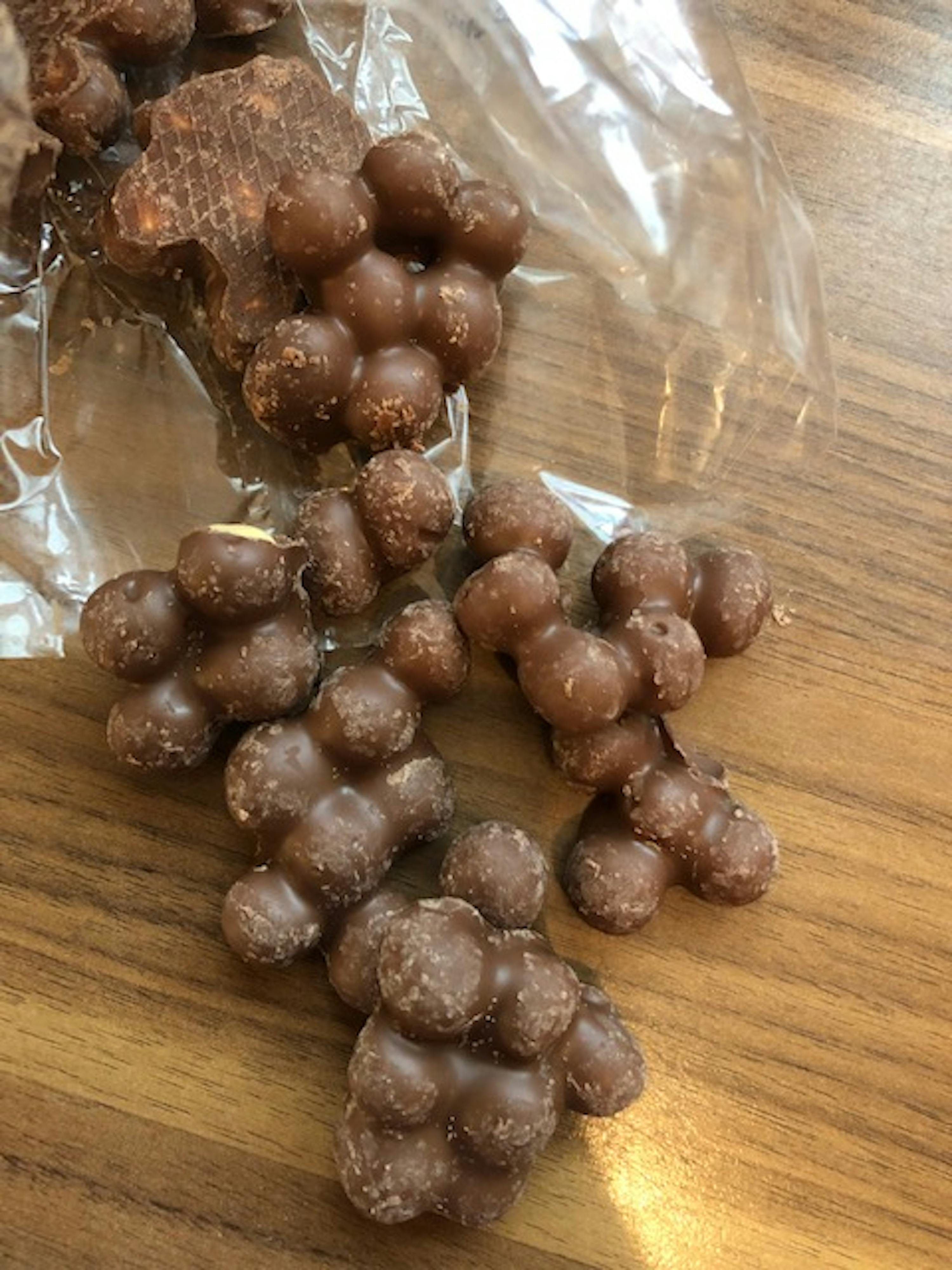 a bag of chocolate covered grapes on a wooden table