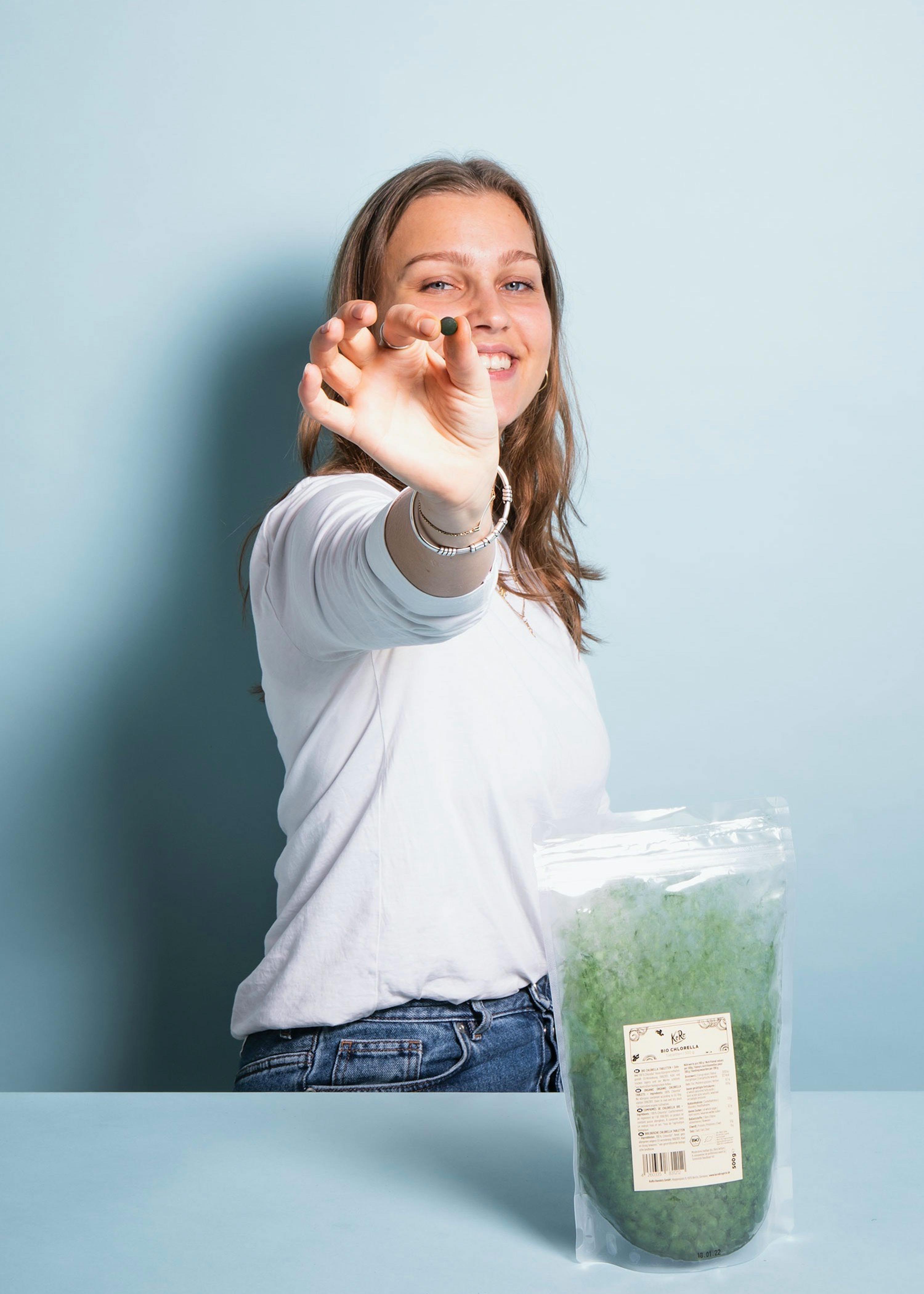 a woman in a white shirt is holding a small green object in her hand