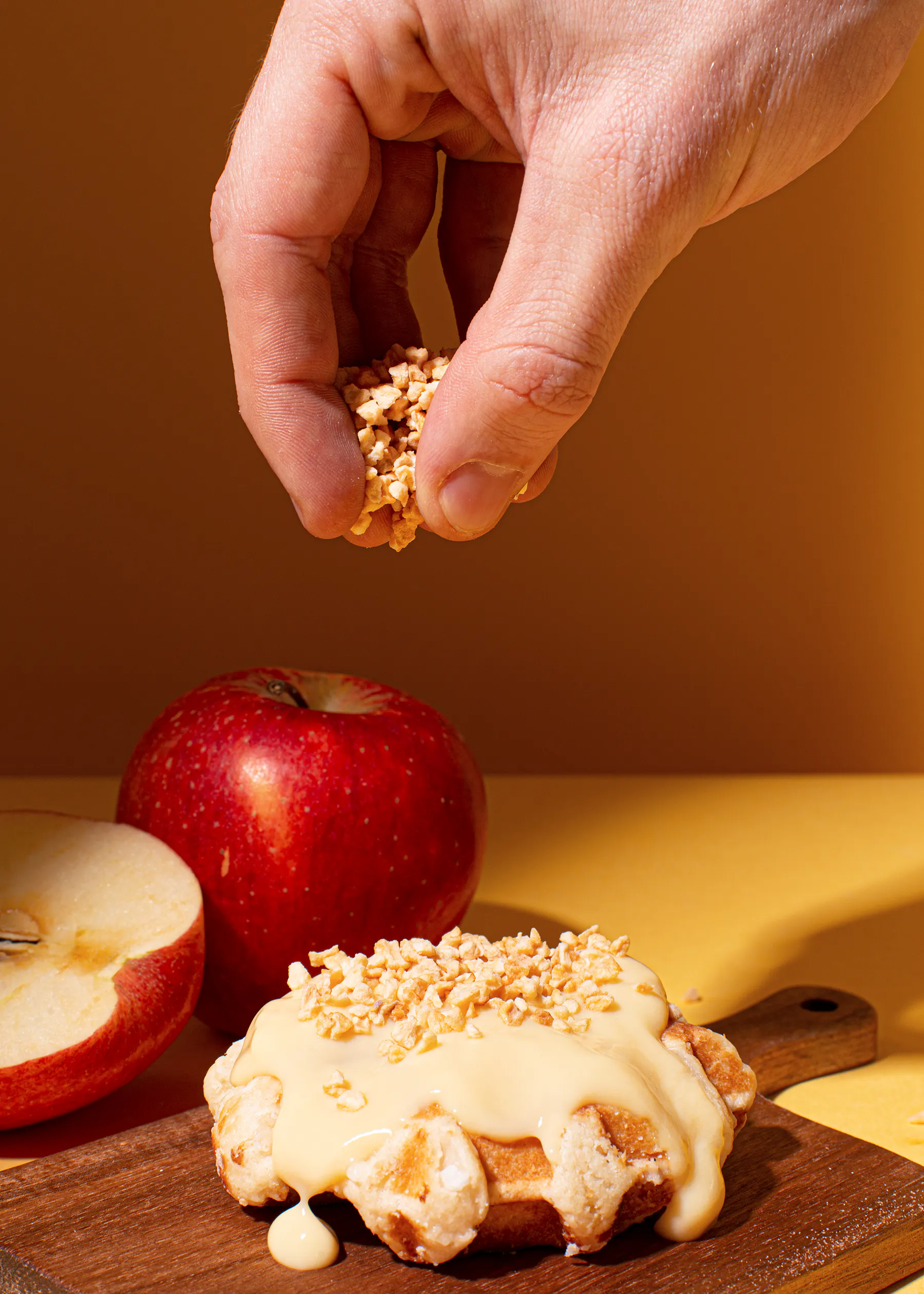 a person is spreading oatmeal on a pastry next to an apple