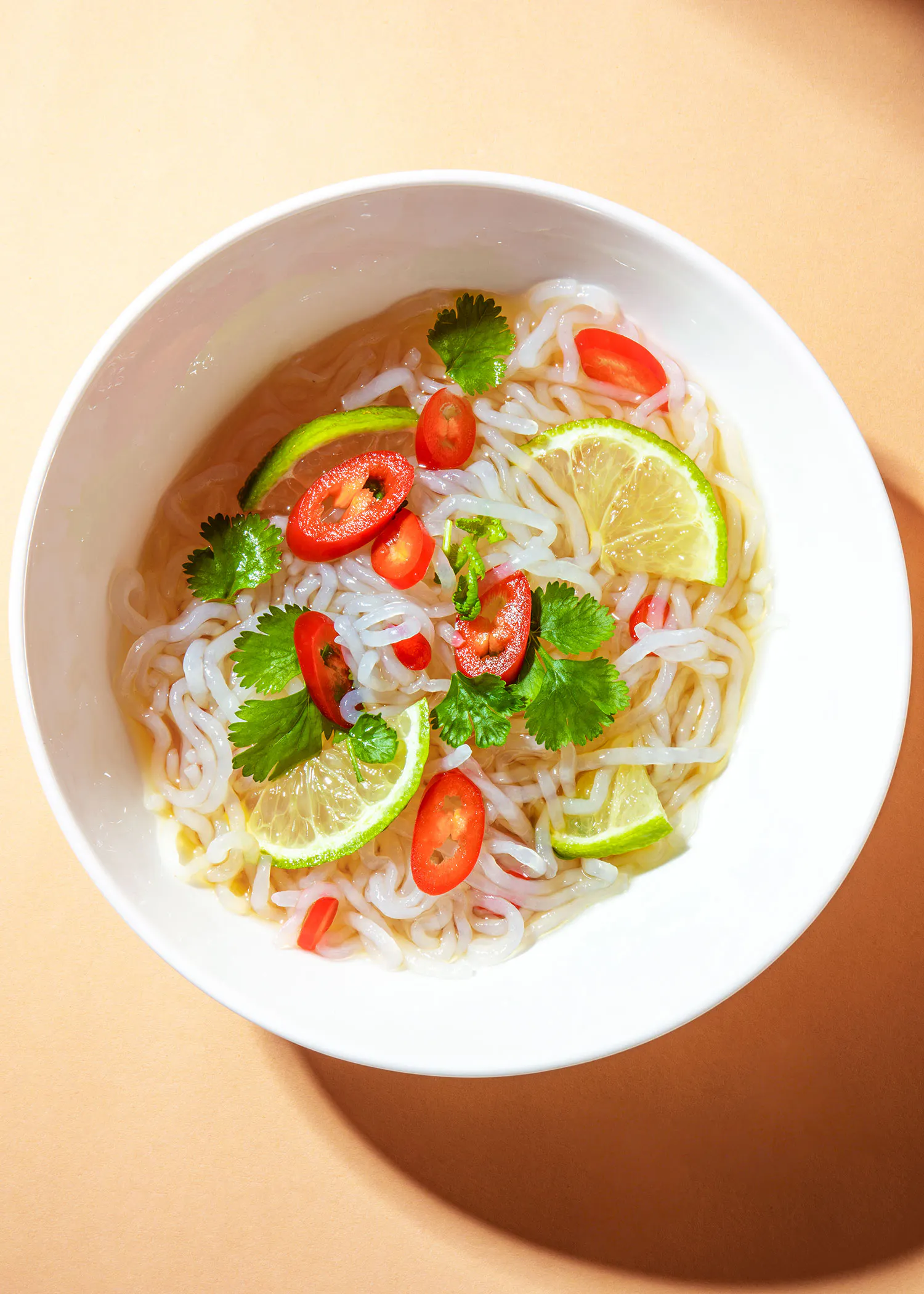 un bol de soupe aux nouilles avec des tomates et des citrons