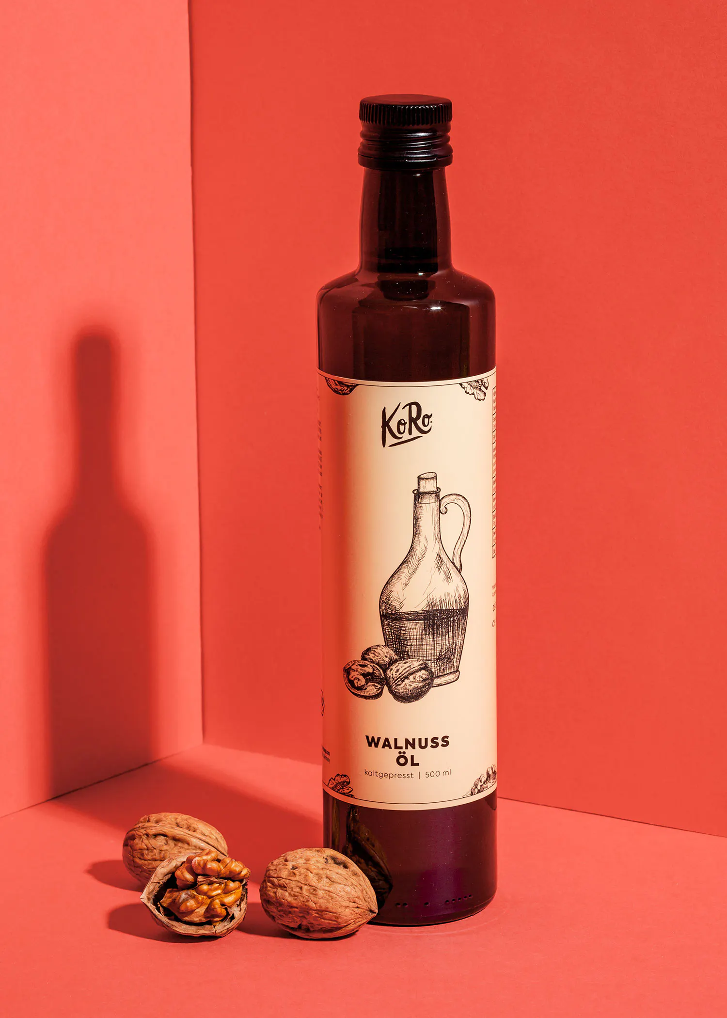 eine Flasche Walnussöl steht auf einem rosa Hintergrund