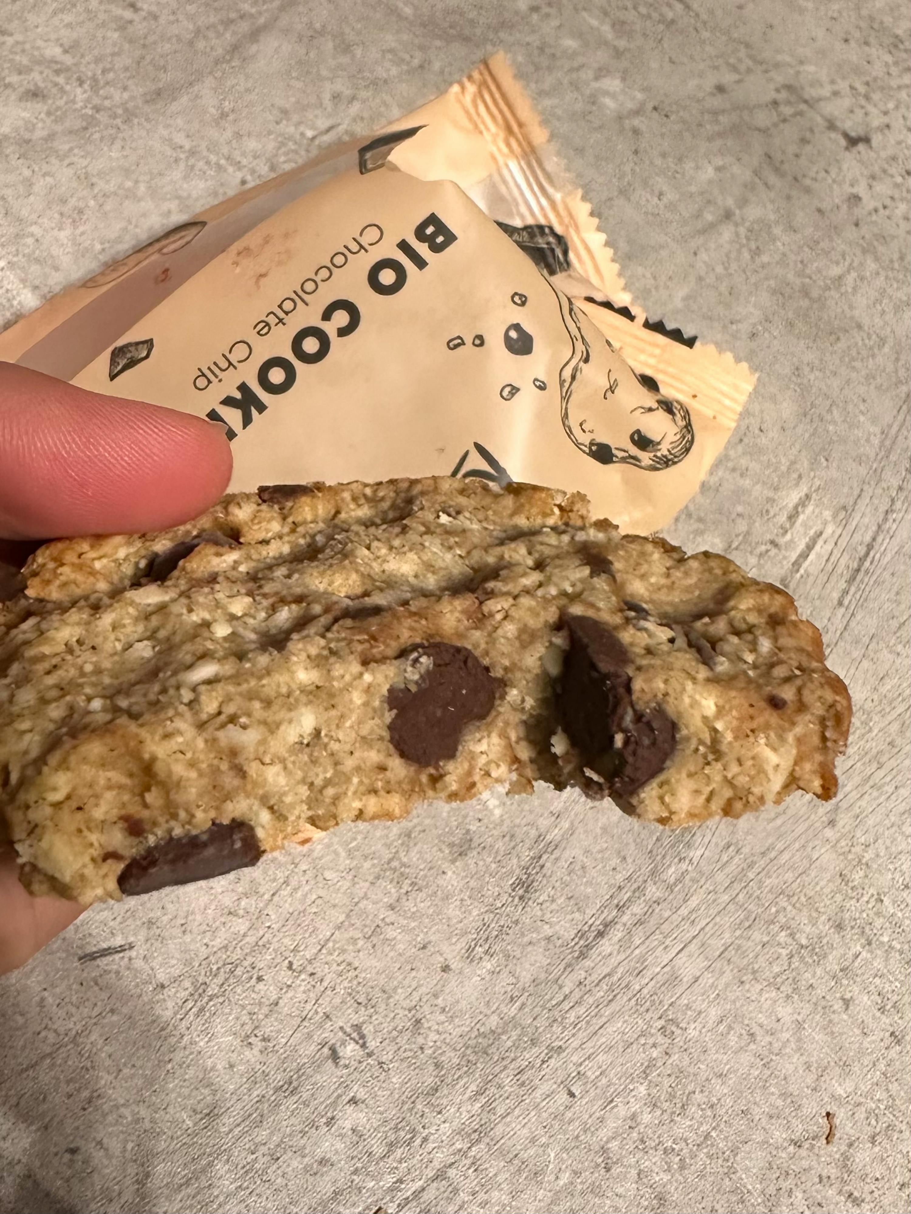 Eine Person hält ein Bio-Keks mit Schokoladenchips in der Hand