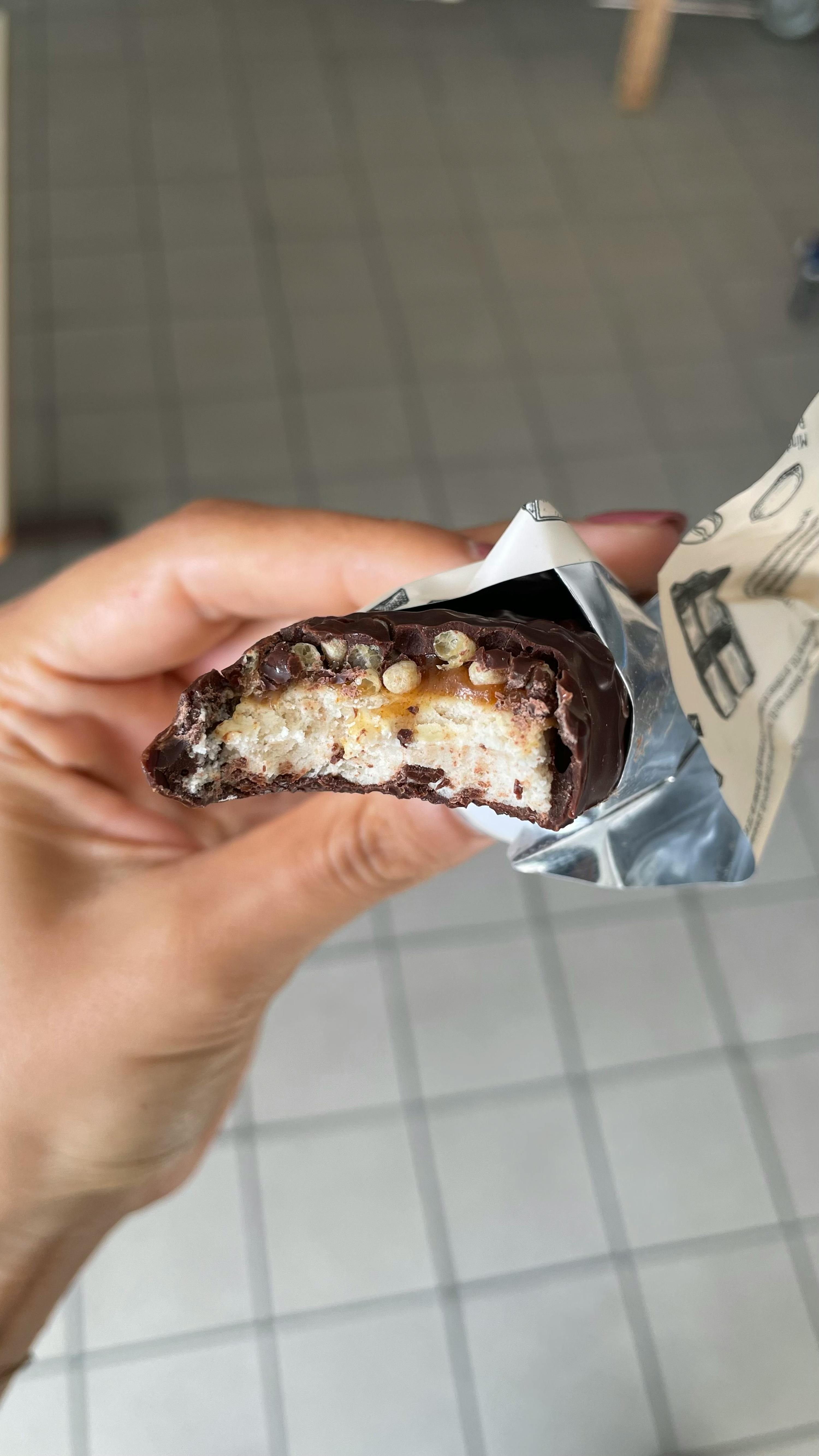 una persona tiene in mano una barretta di cioccolato con una fetta tagliata fuori