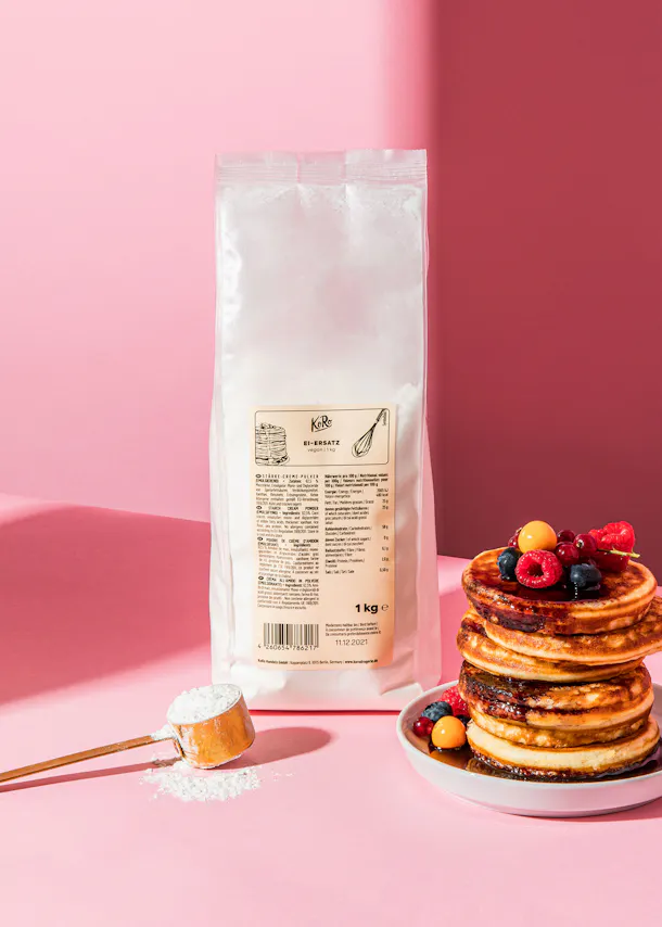 ein Stapel Pfannkuchen auf einem Teller neben einer Packung mehl