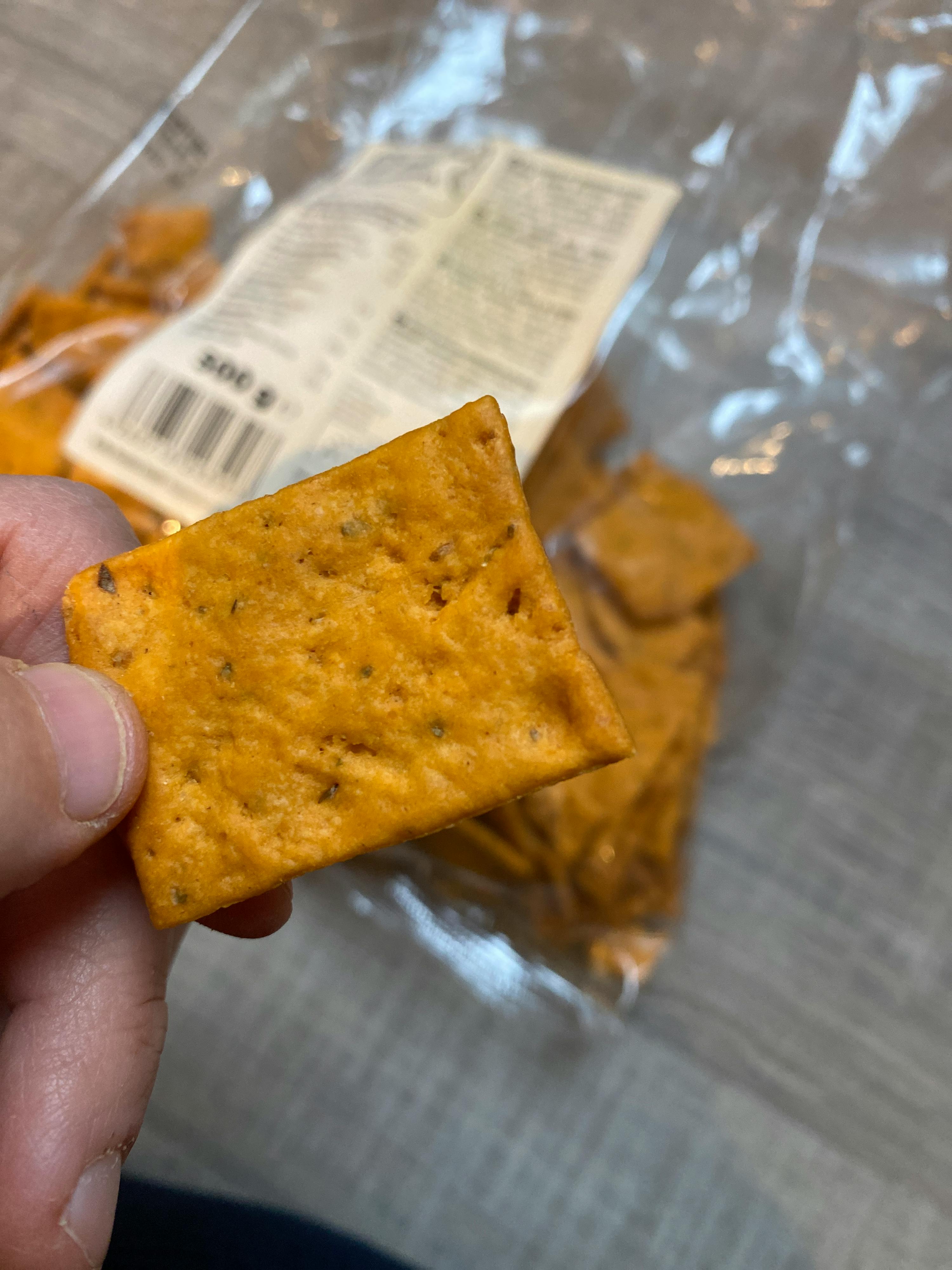 una persona tiene in mano un pezzo di cracker e un sacchetto di cracker