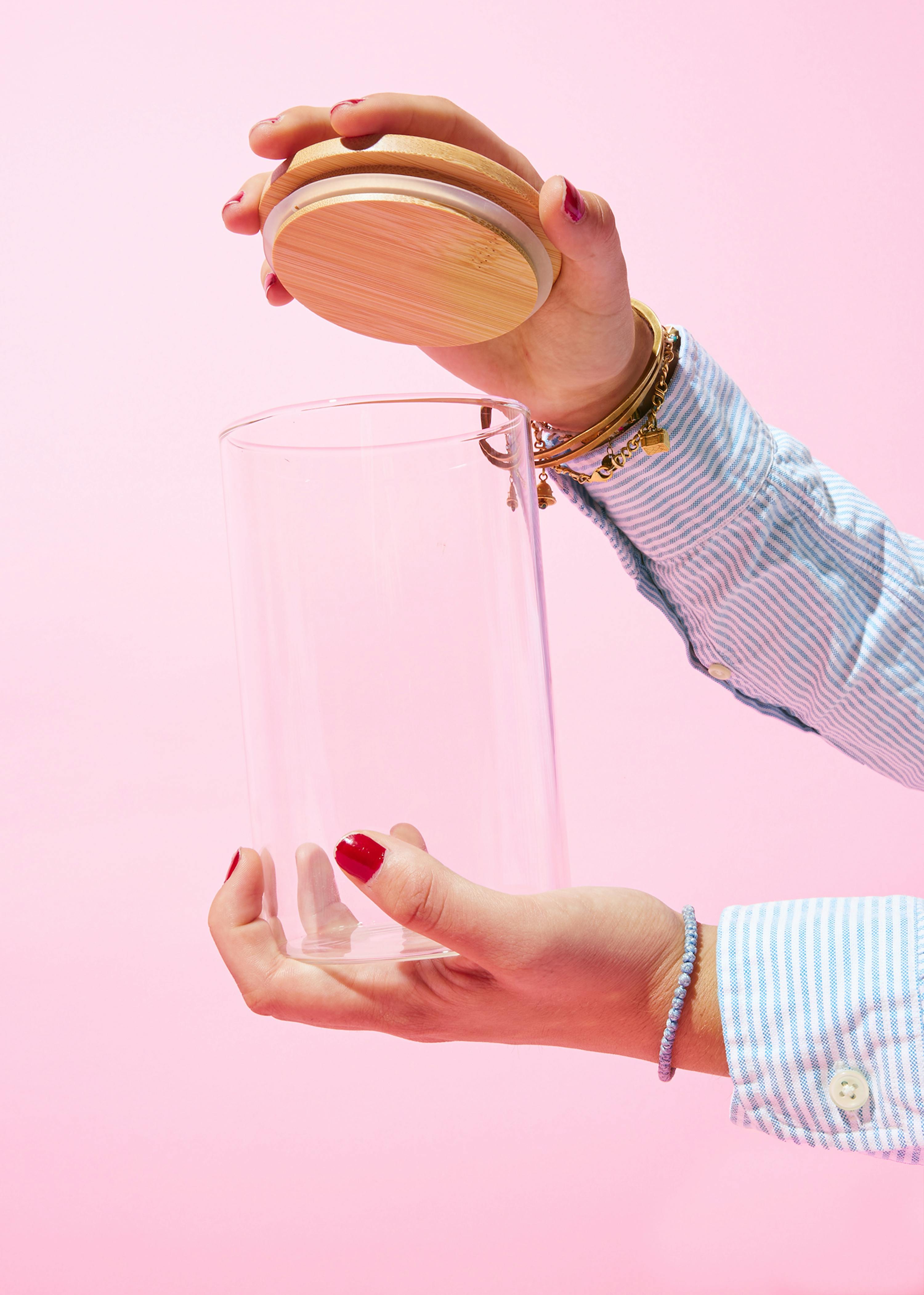 Eine Frau hält ein Glasgefäß mit einem Holzdeckel in ihren Händen