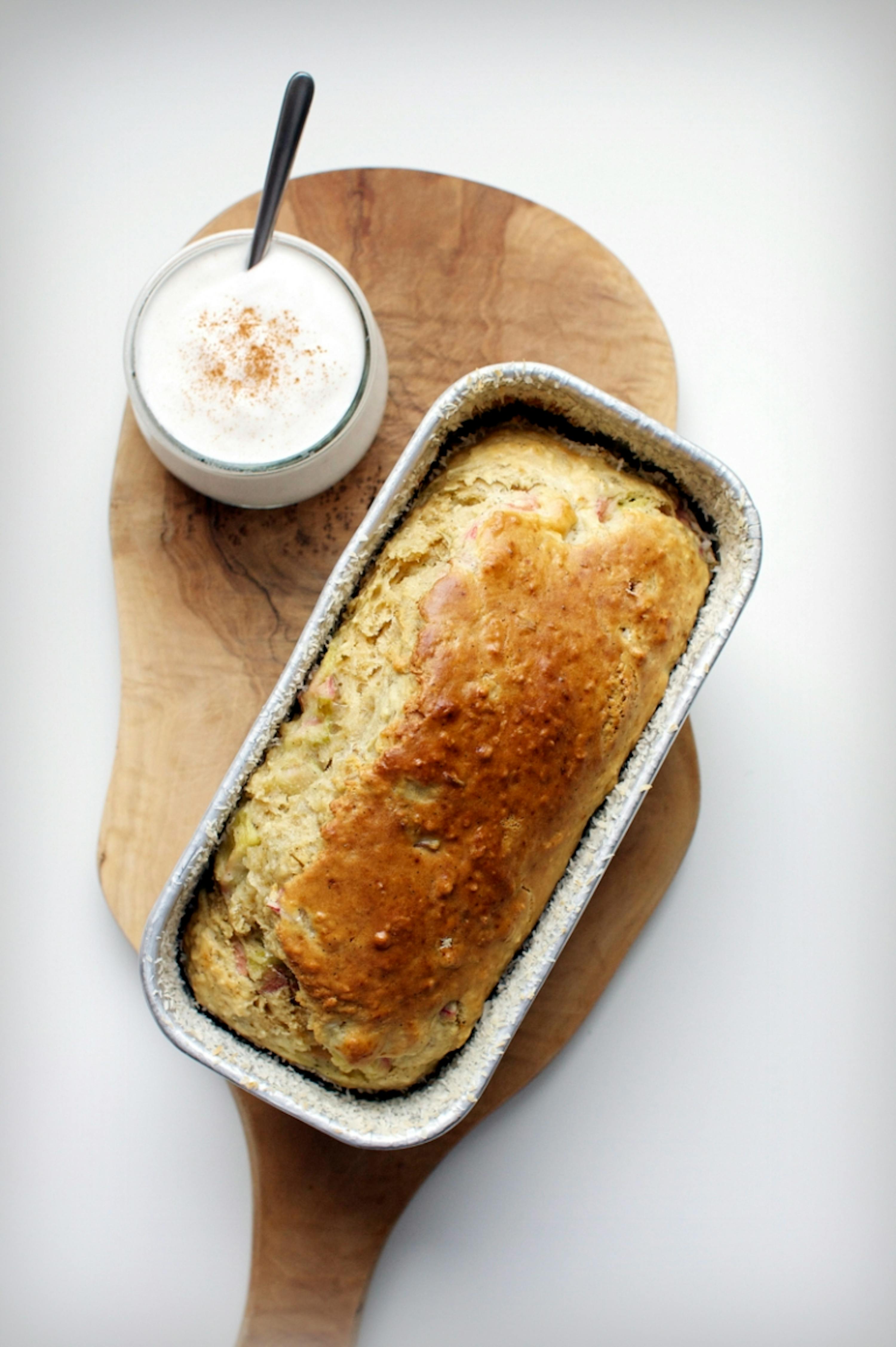 une miche de pain est assise sur une planche à découper en bois à côté d' une tasse de cappuccino