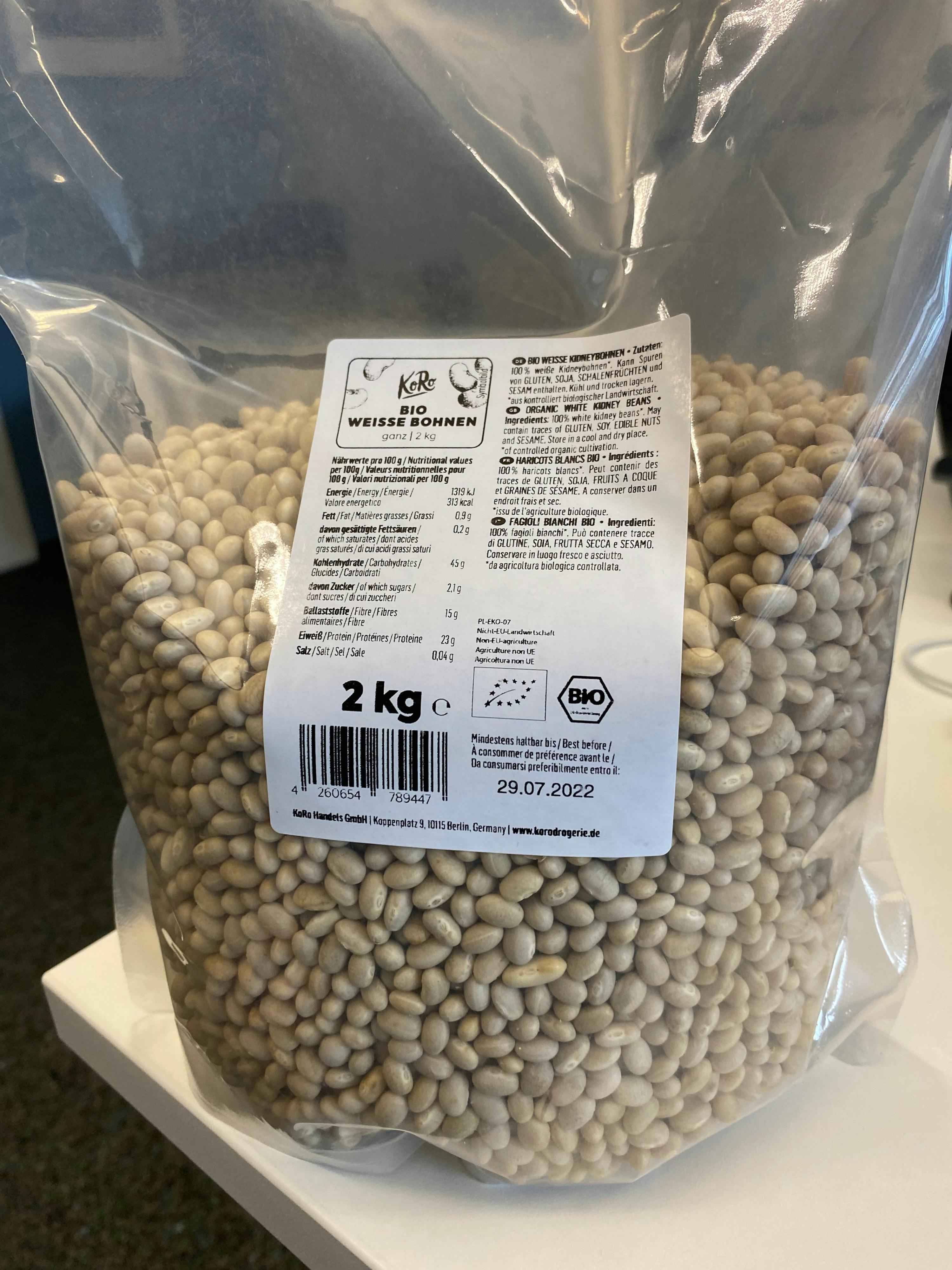 eine Plastiktüte mit weißen Bohnen steht auf einem weißen Tisch