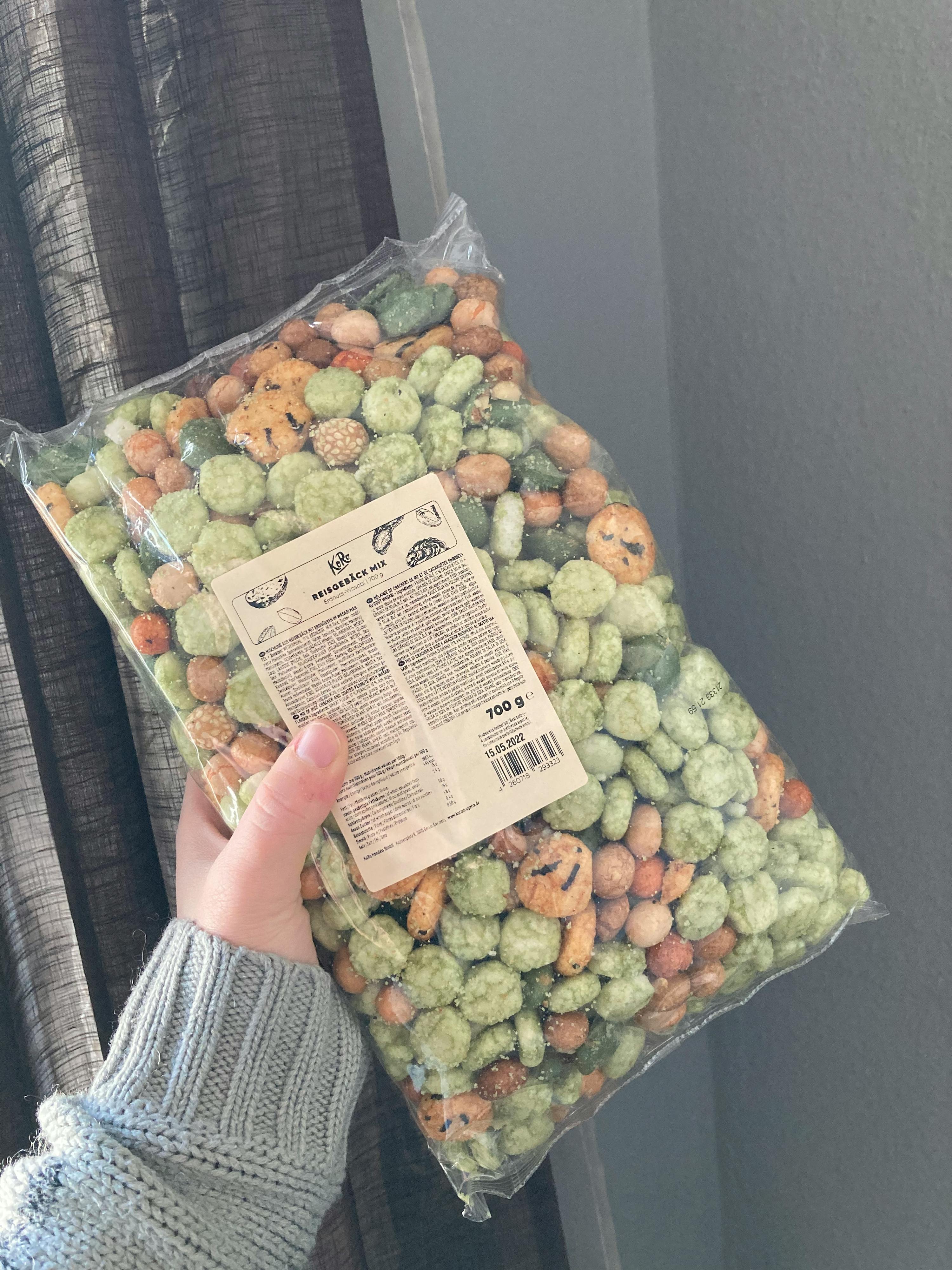 a person is holding a bag of mixed nuts and crackers