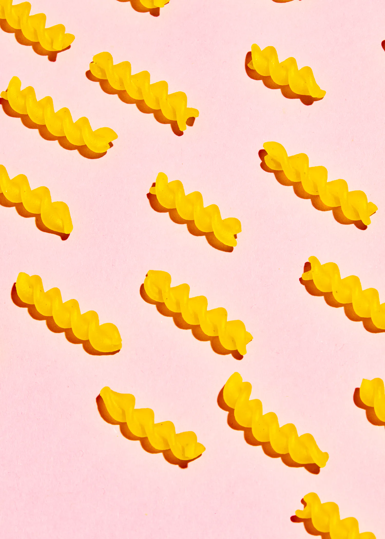 a row of yellow pasta on a pink background