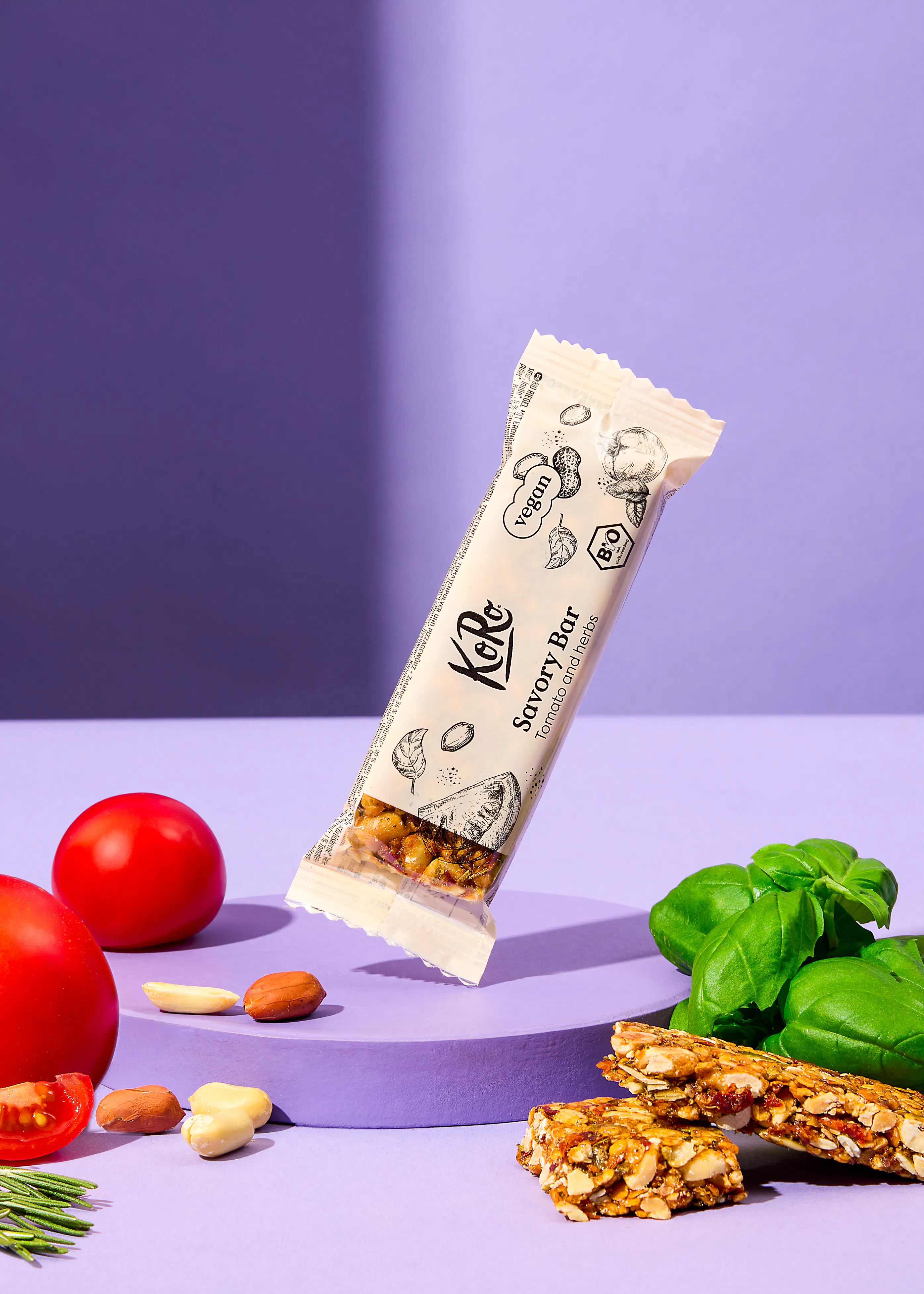 une barre savoureuse est posée sur une table violette entourée de tomates et de basilic