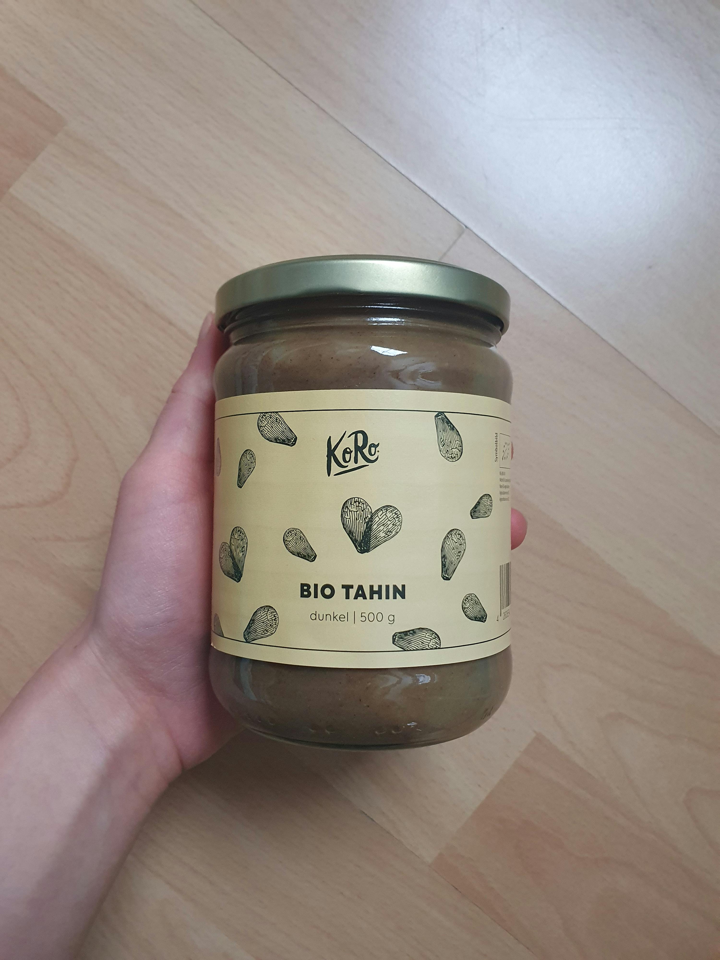 une personne tient un pot de tahin bio dans sa main