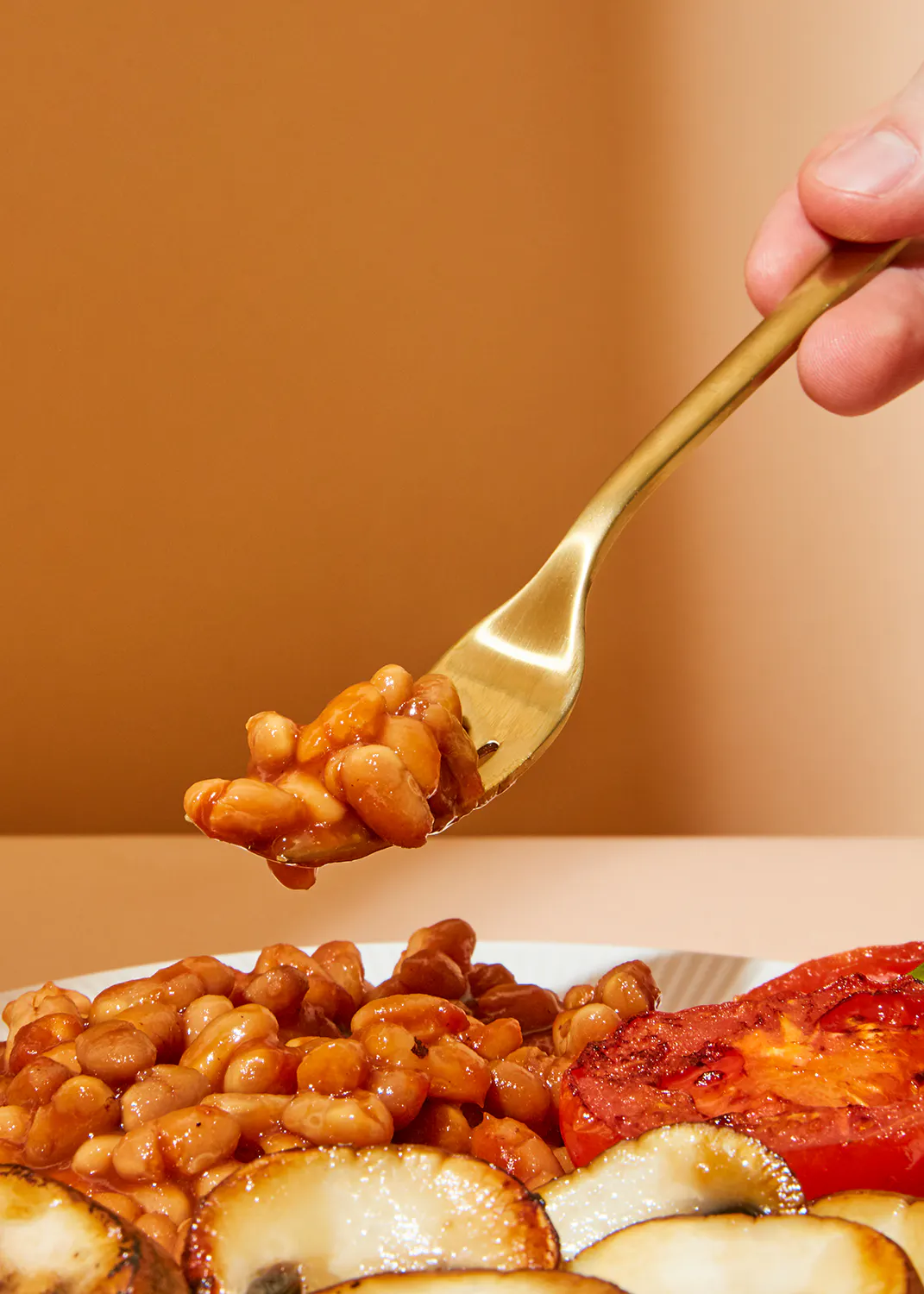 eine Person schöpft Bohnen aus einem Löffel auf einem Teller