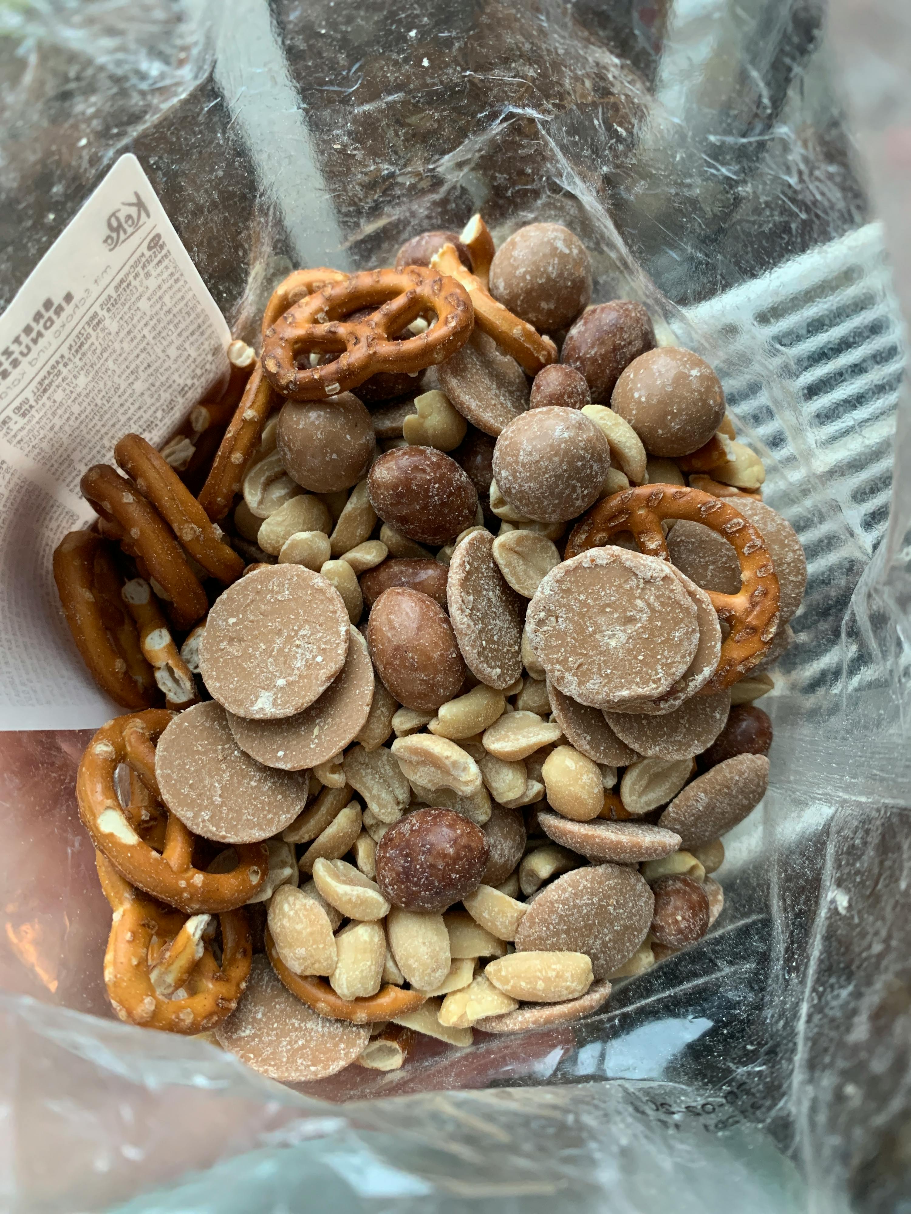 un sac en plastique contient un mélange de noix et de bretzels