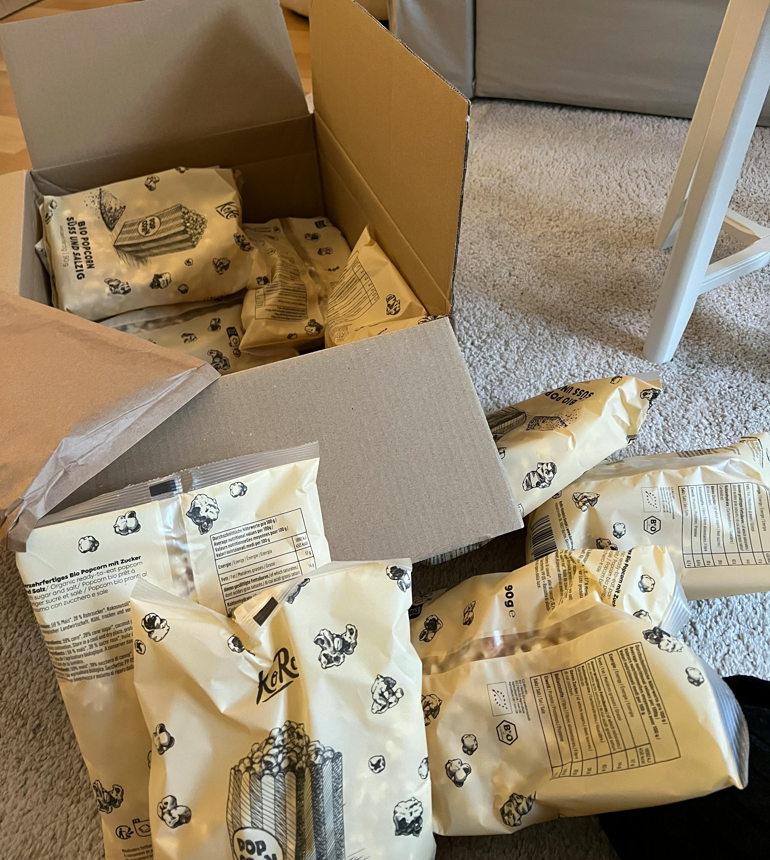 una scatola piena di sacchetti di popcorn è seduta su un tappeto