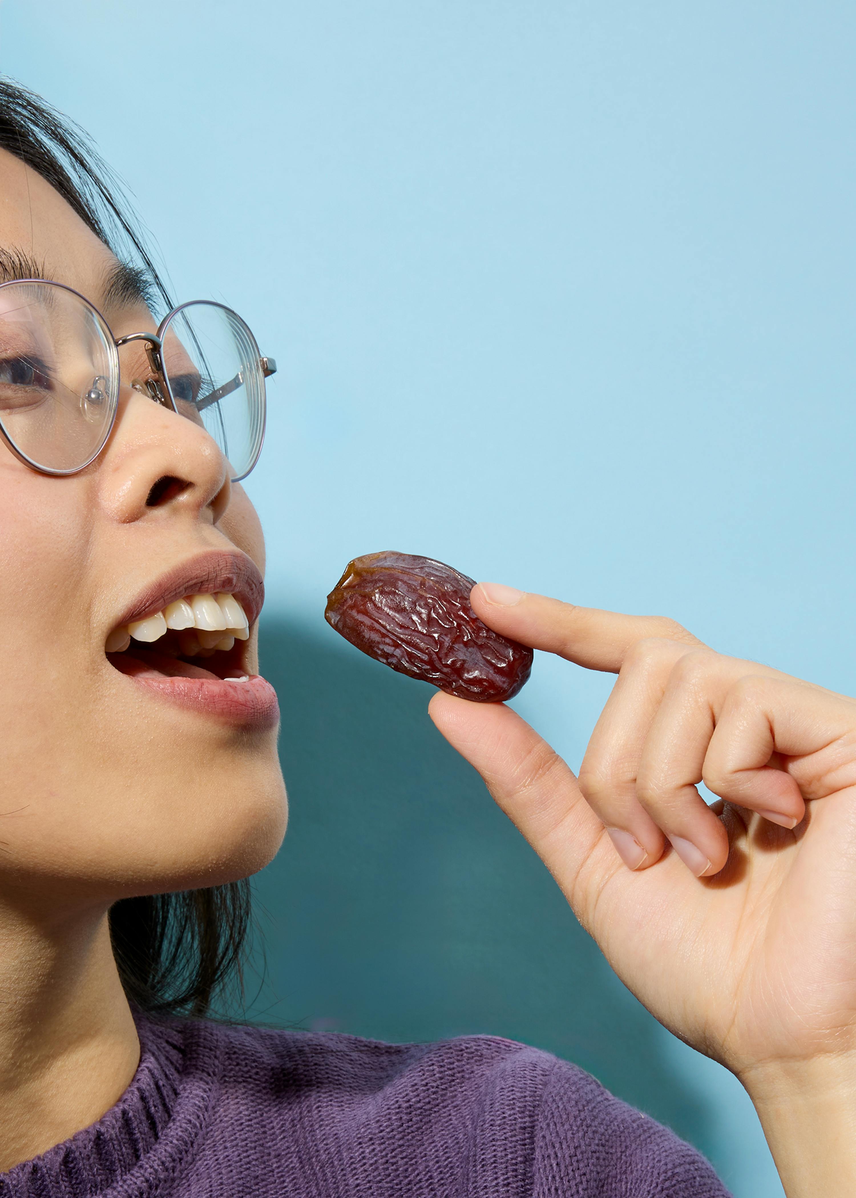 una donna che indossa gli occhiali mangia una dattera