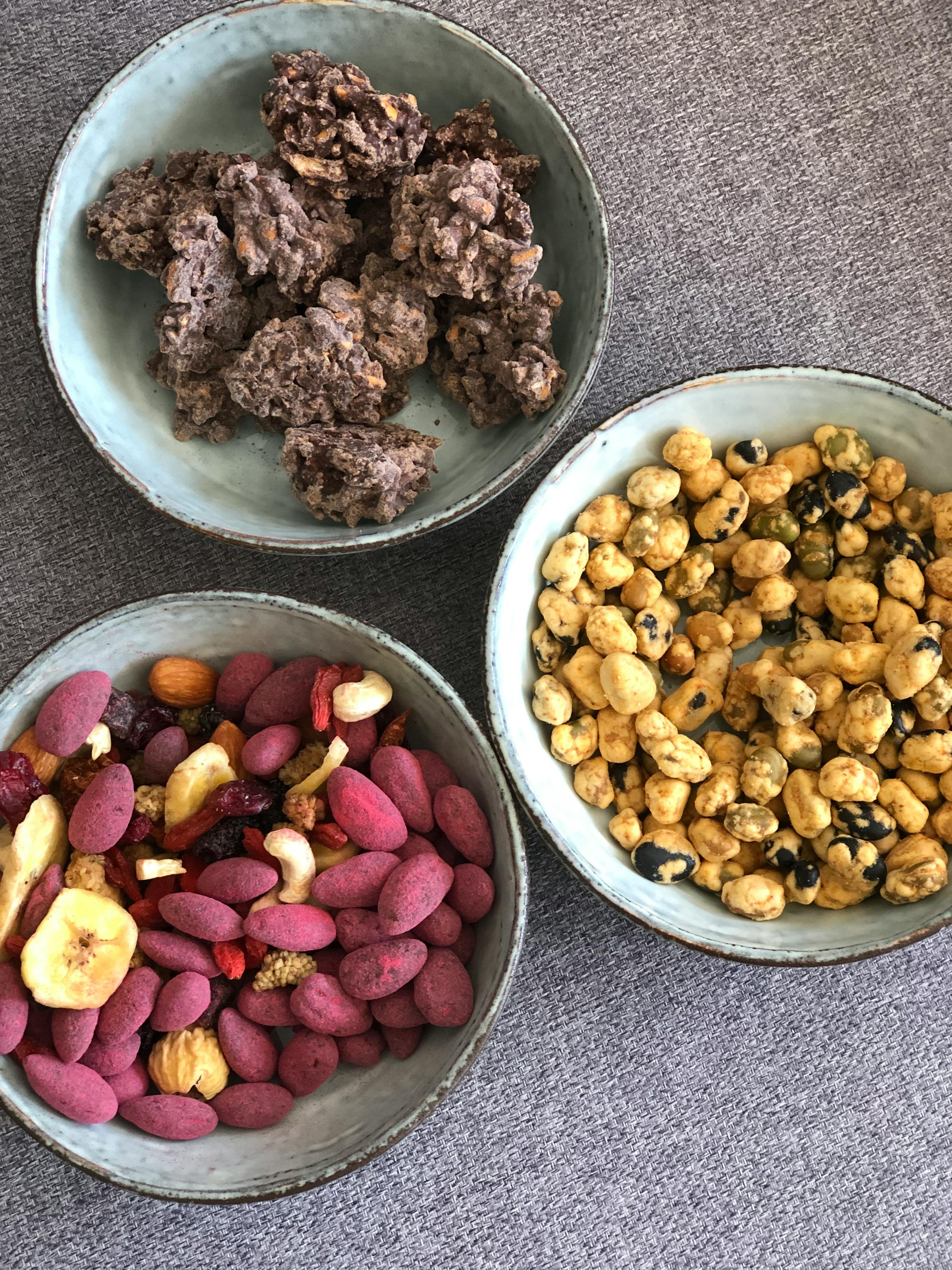 drei Schüsseln mit verschiedenen Arten von Nüssen und Trockenfrüchten