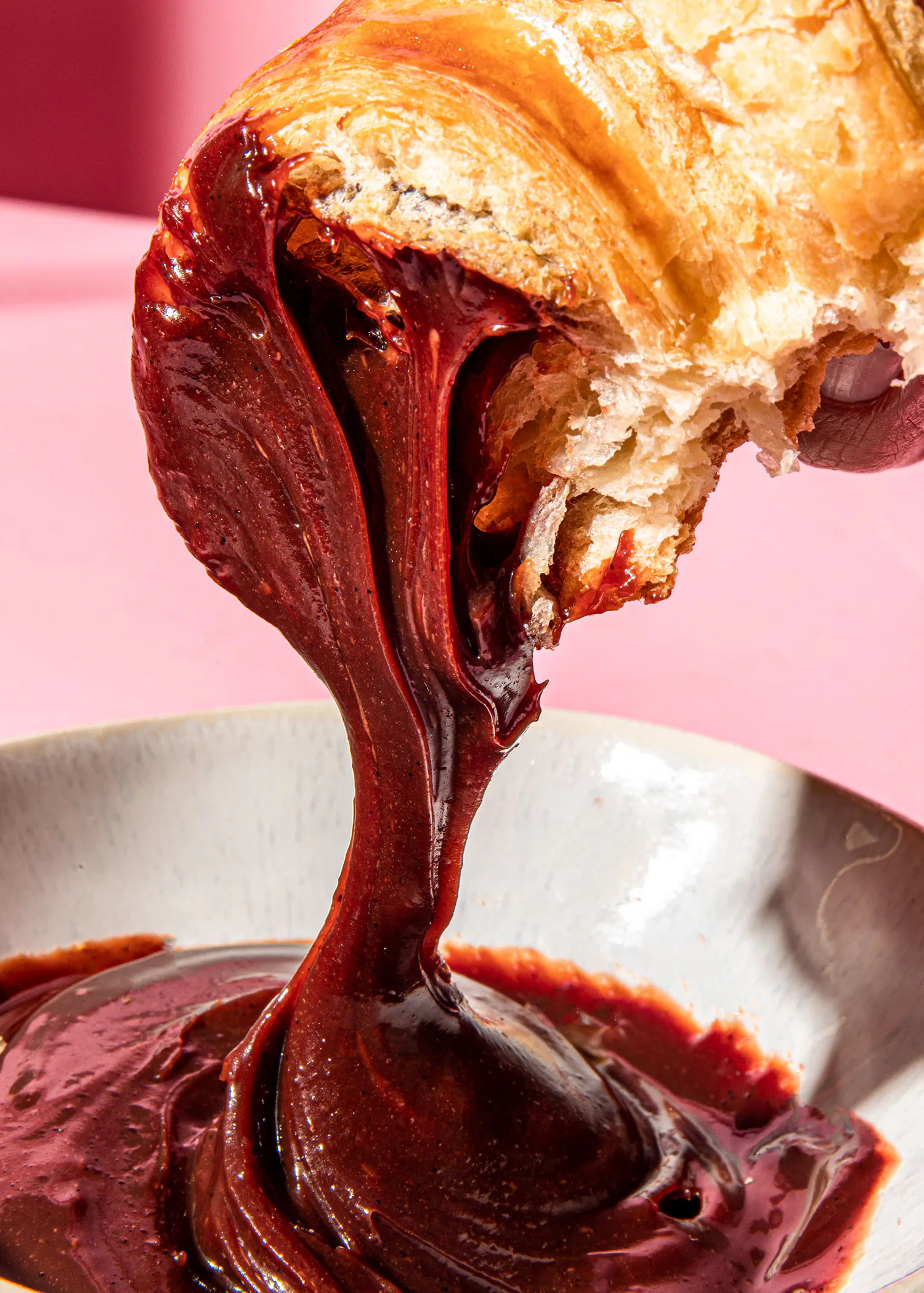 un morceau de pain est versé dans un bol de sauce au chocolat