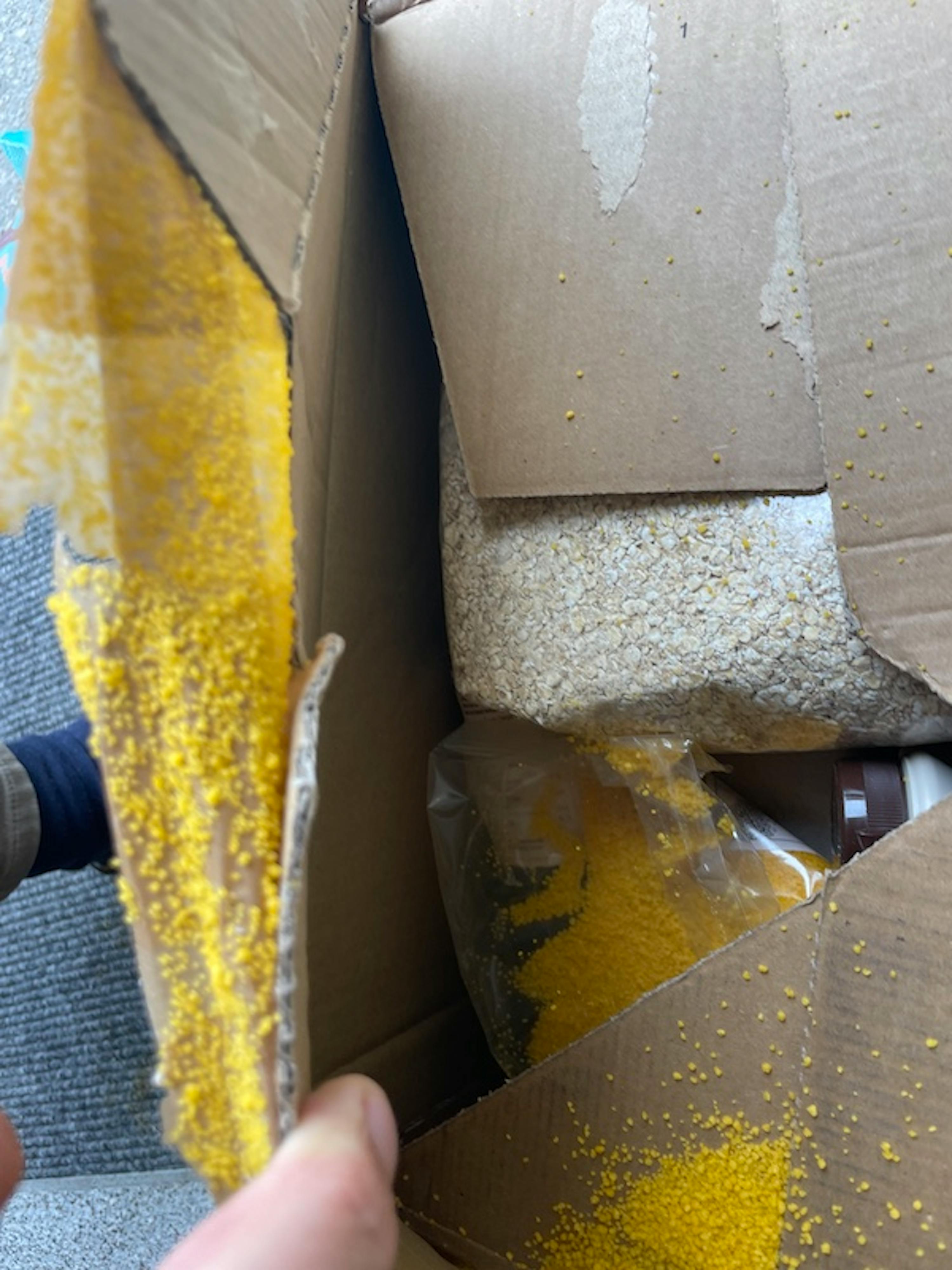 eine Person hält einen Karton mit einem Stück gelben Stoff darin