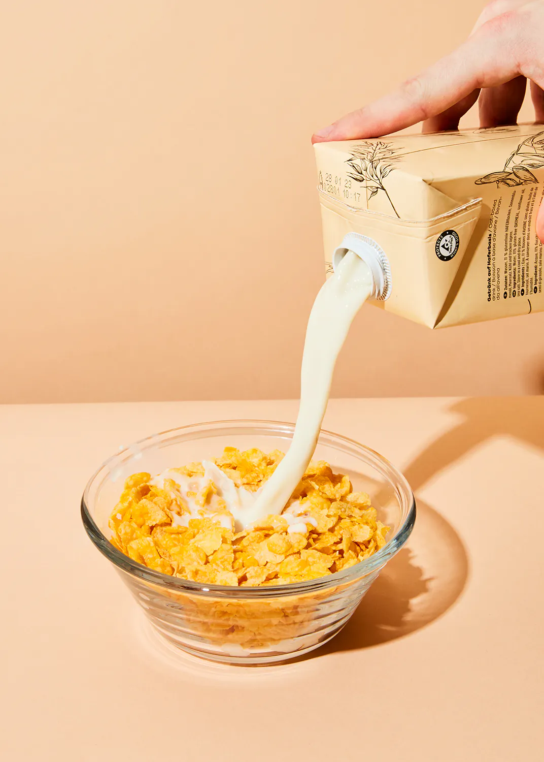 une personne verse du lait dans un bol de flocons de maïs