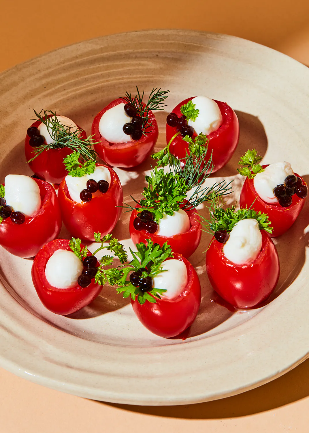 un plato blanco lleno de tomates rellenos de queso y bayas