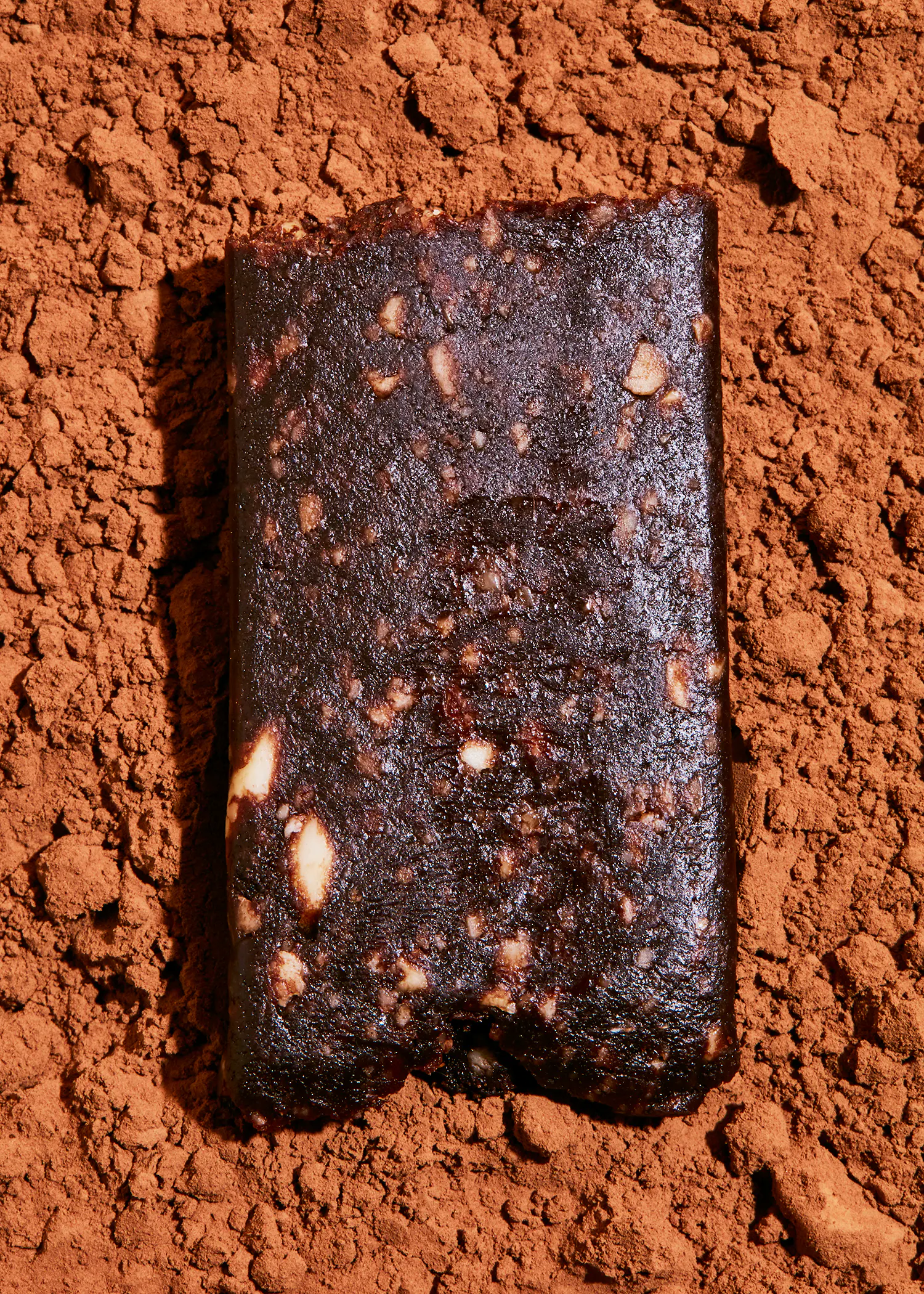 une barre de chocolat est assise sur un tas de poudre de cacao