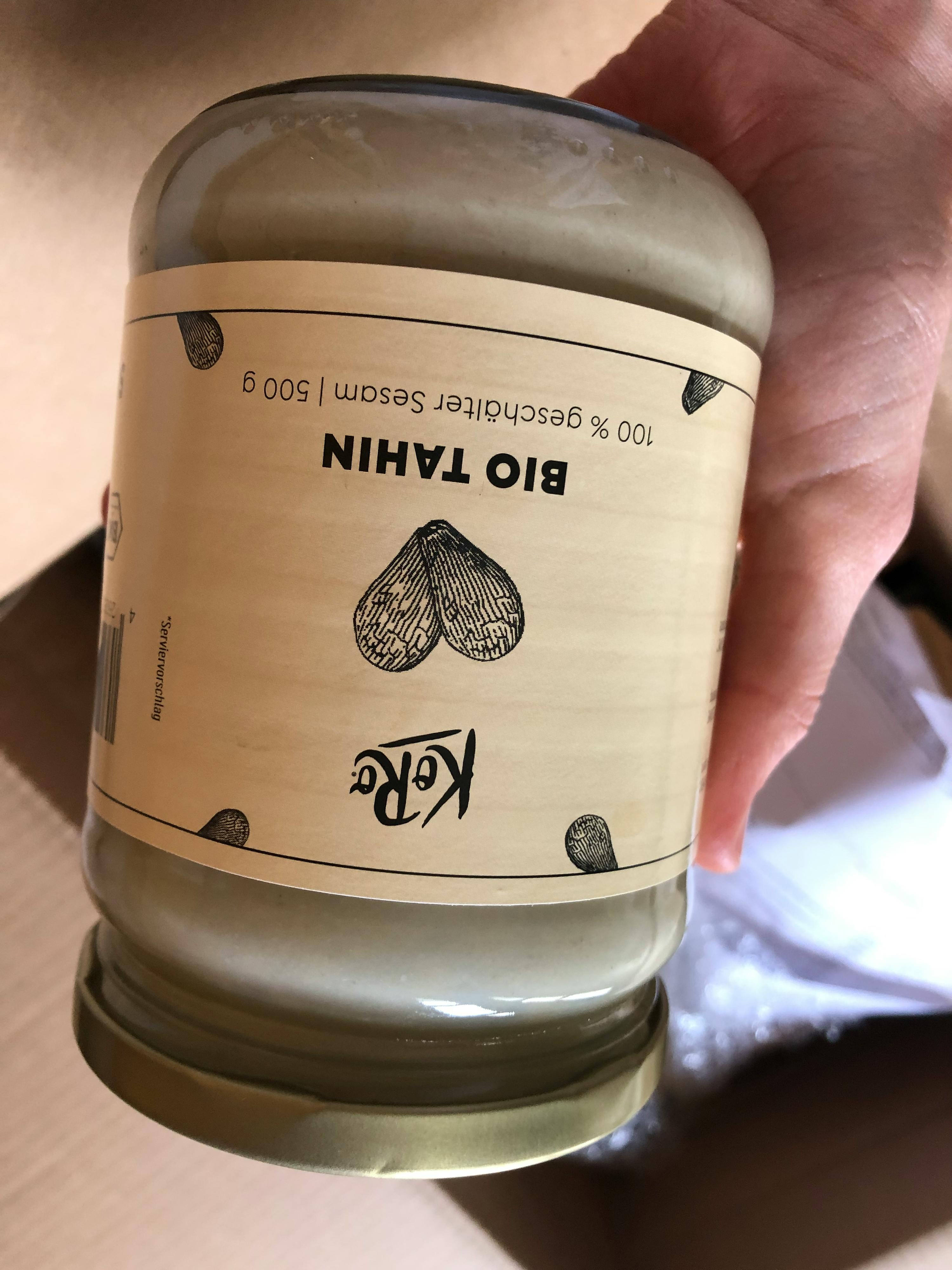 eine Person hält ein Glas Bio-Tahin in der Hand