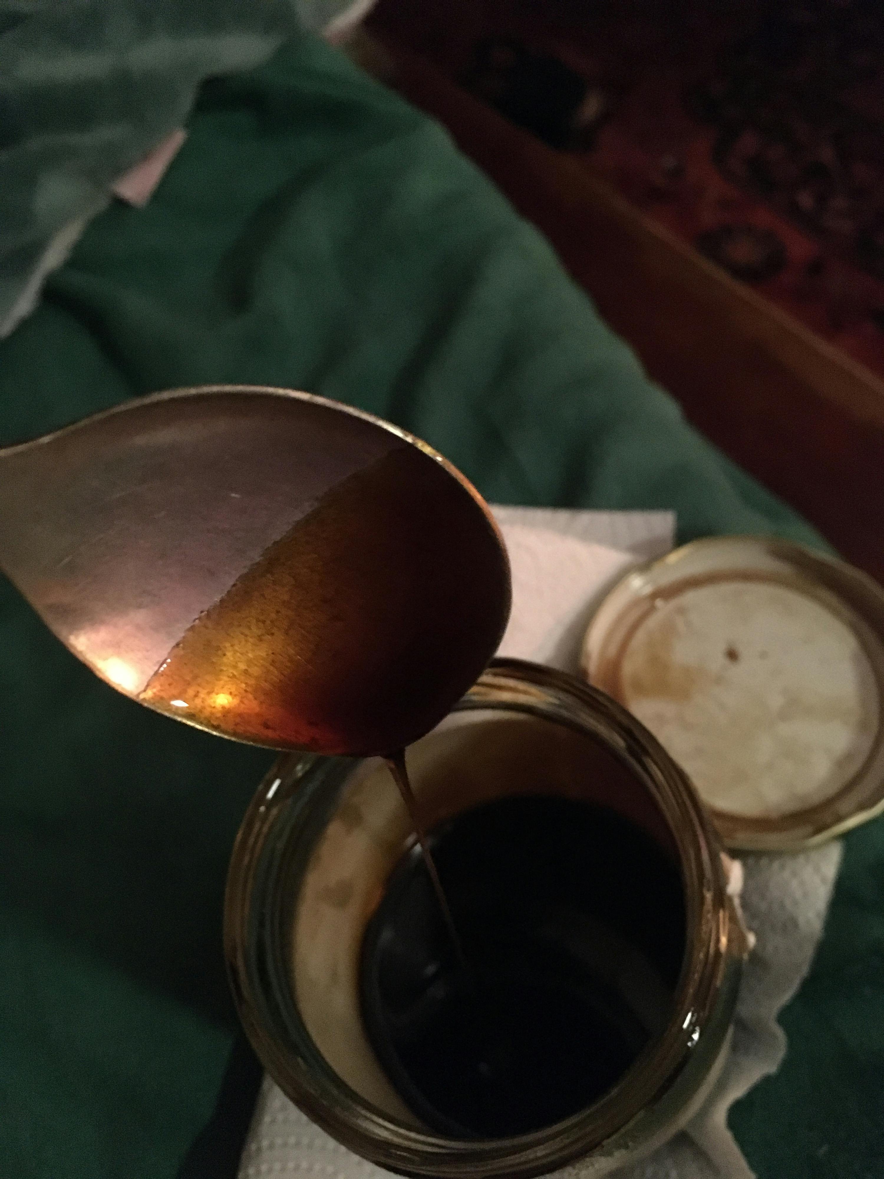 une cuillère est versée dans un bocal rempli d' un liquide brun