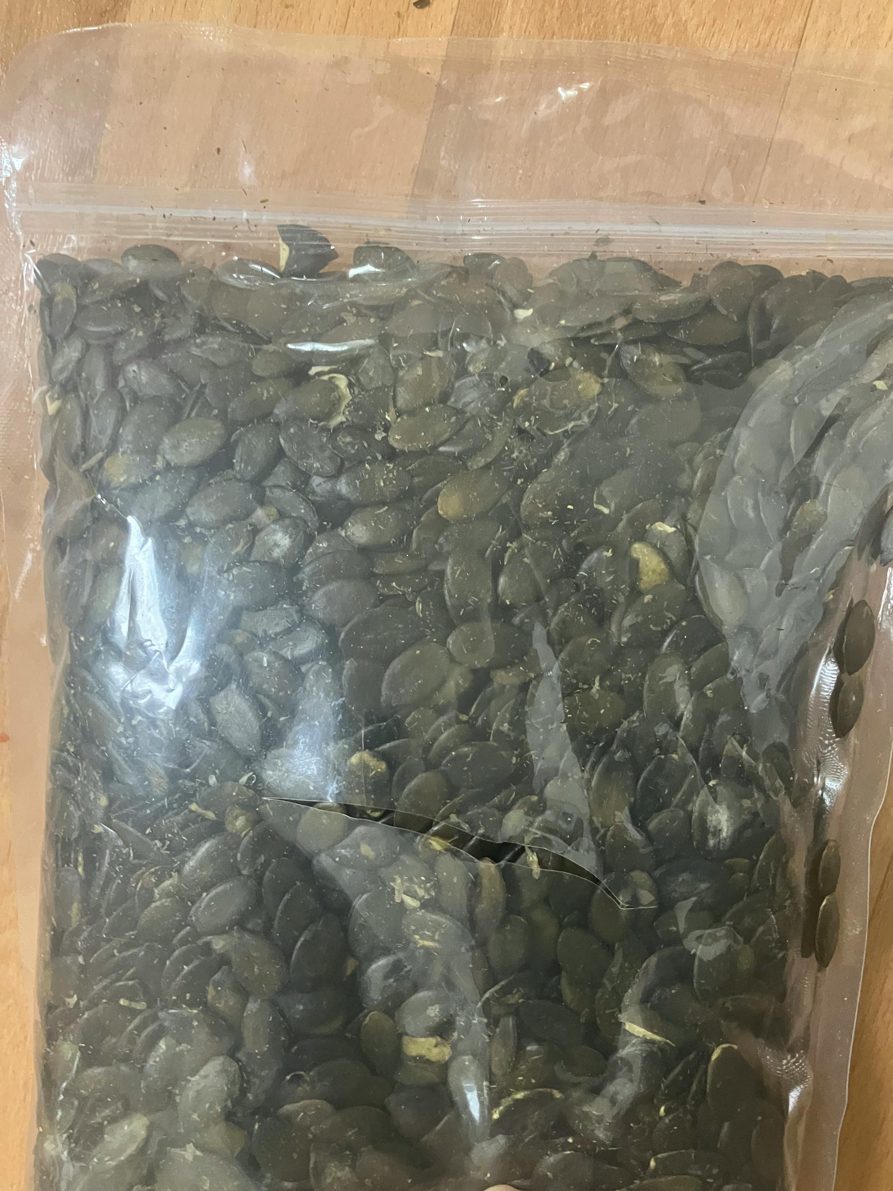 un sacchetto di plastica trasparente pieno di semi di zucca verde scuro.