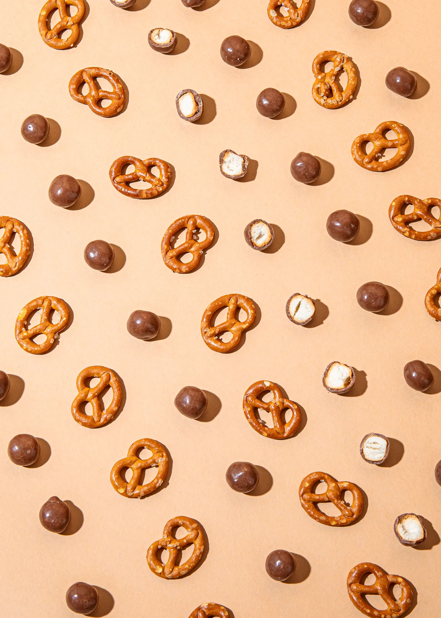 ein nahtloses Muster aus Brezeln und Schokoladenbonbons auf einem braunen Hintergrund