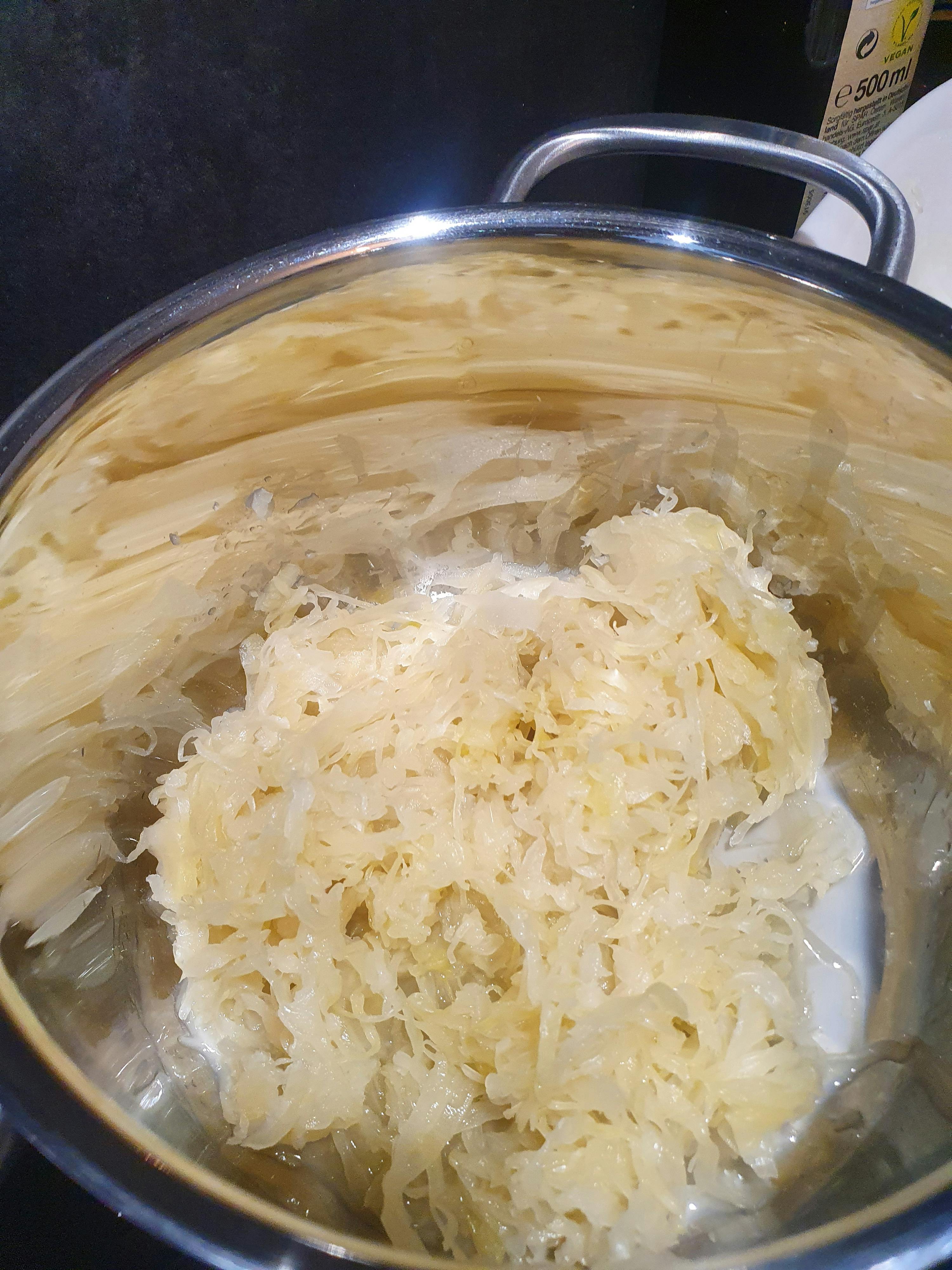 un pot rempli de pâtes et de choucroute avec une bouteille de 500 ml à l' arrière