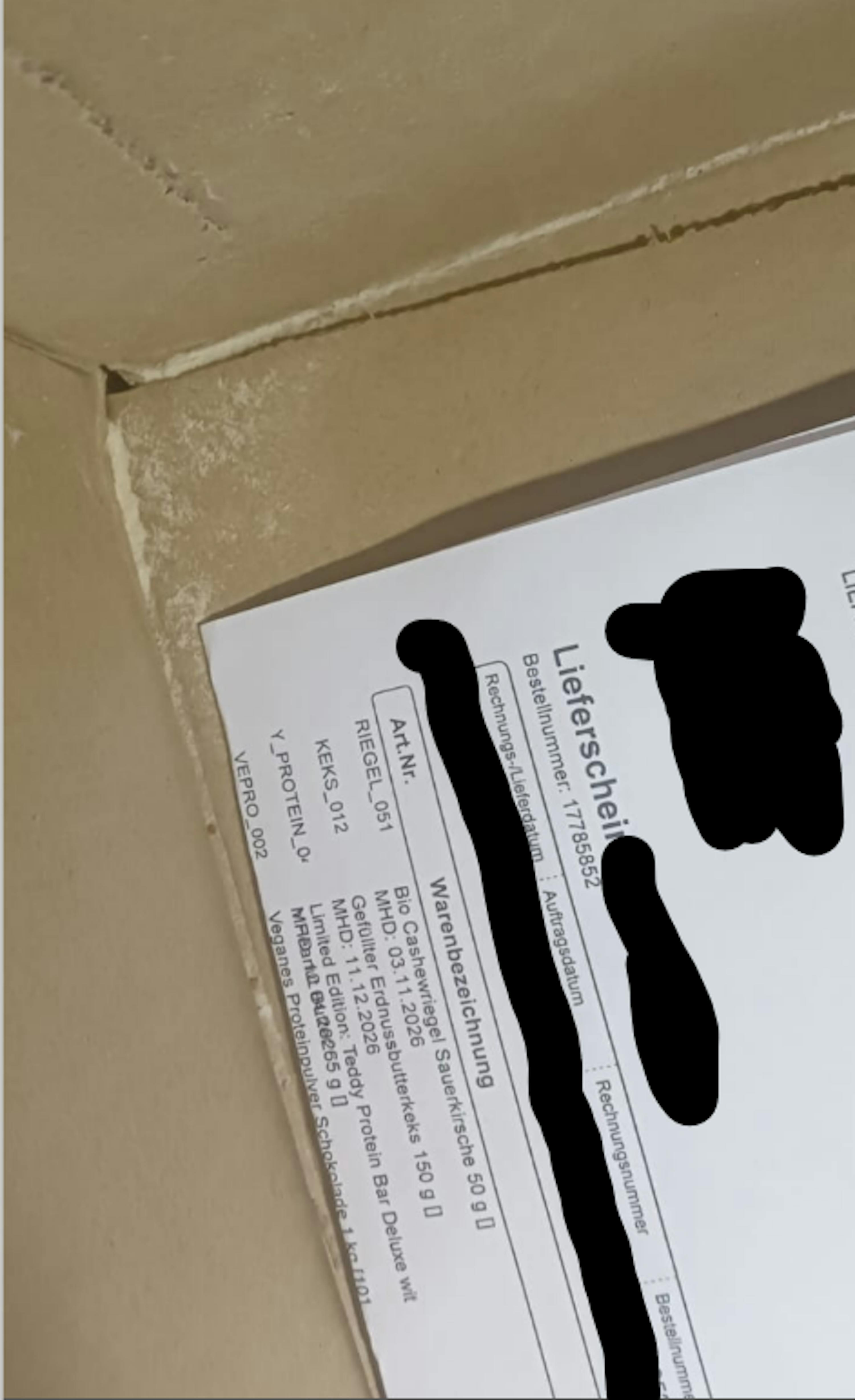 un bon de livraison partiellement visible avec des détails de produits, posé sur une surface beige poussiéreuse.