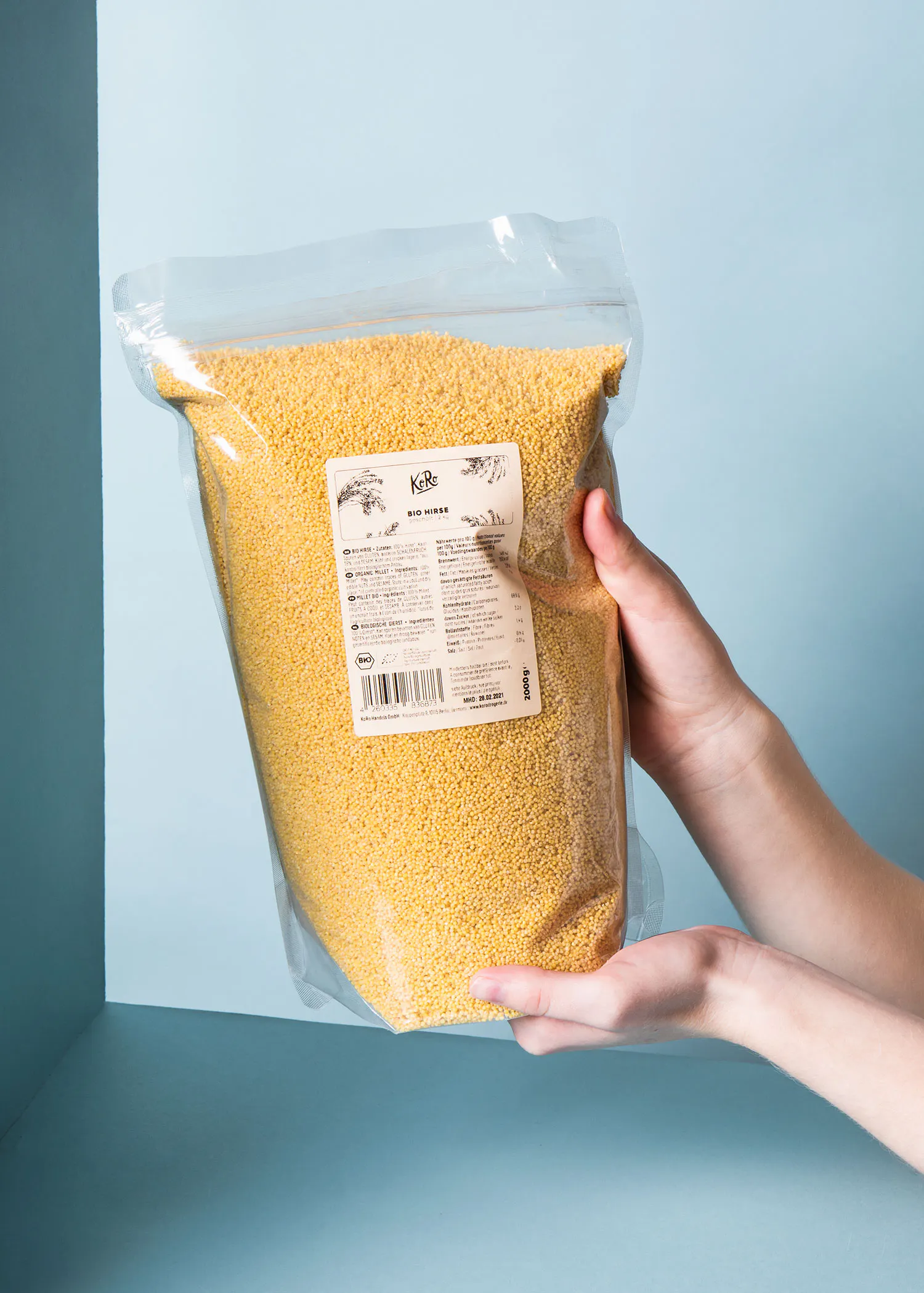 une personne tient un sac de millet bio dans leur main