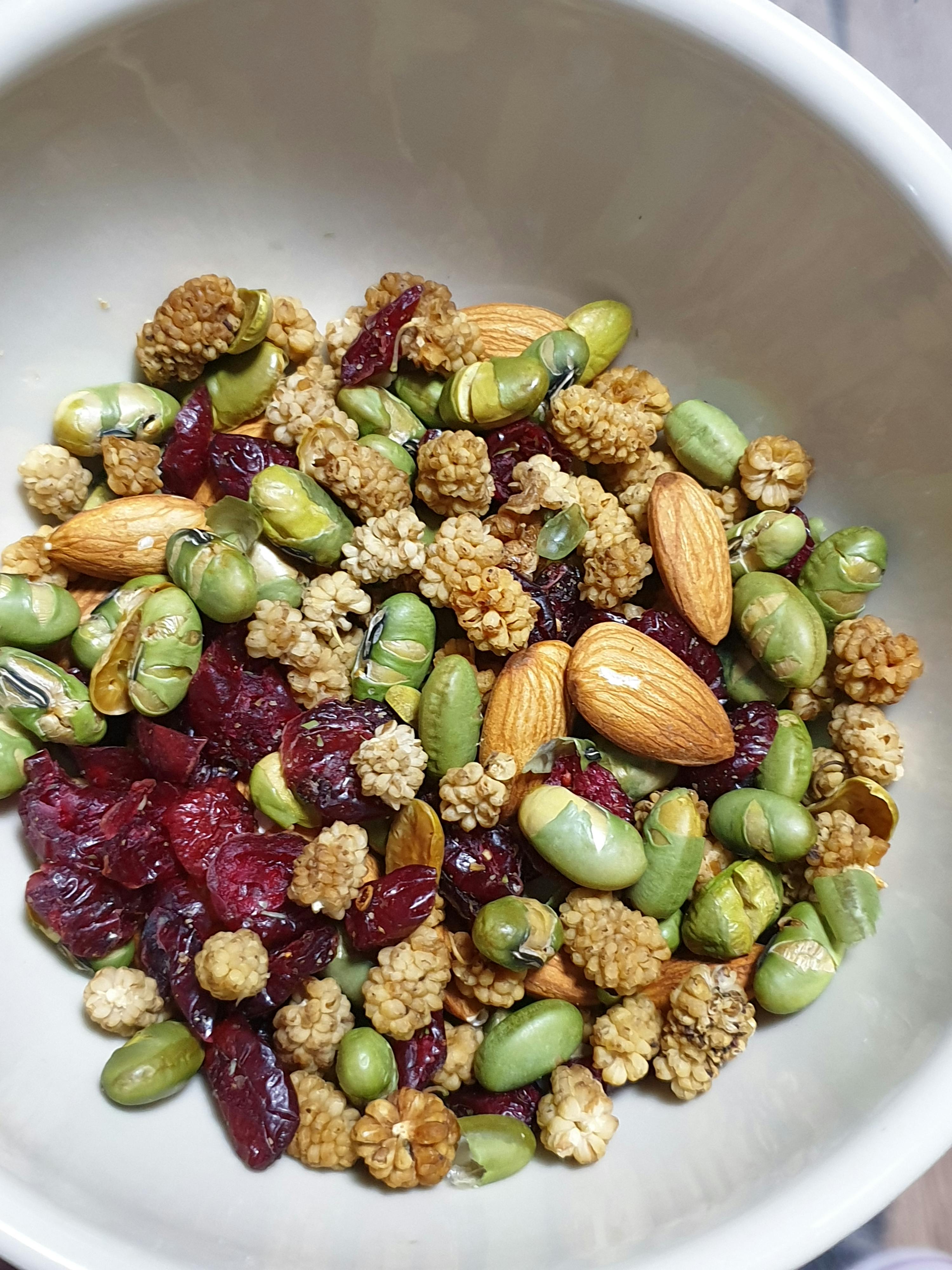 a white bowl filled with nuts and cranberries